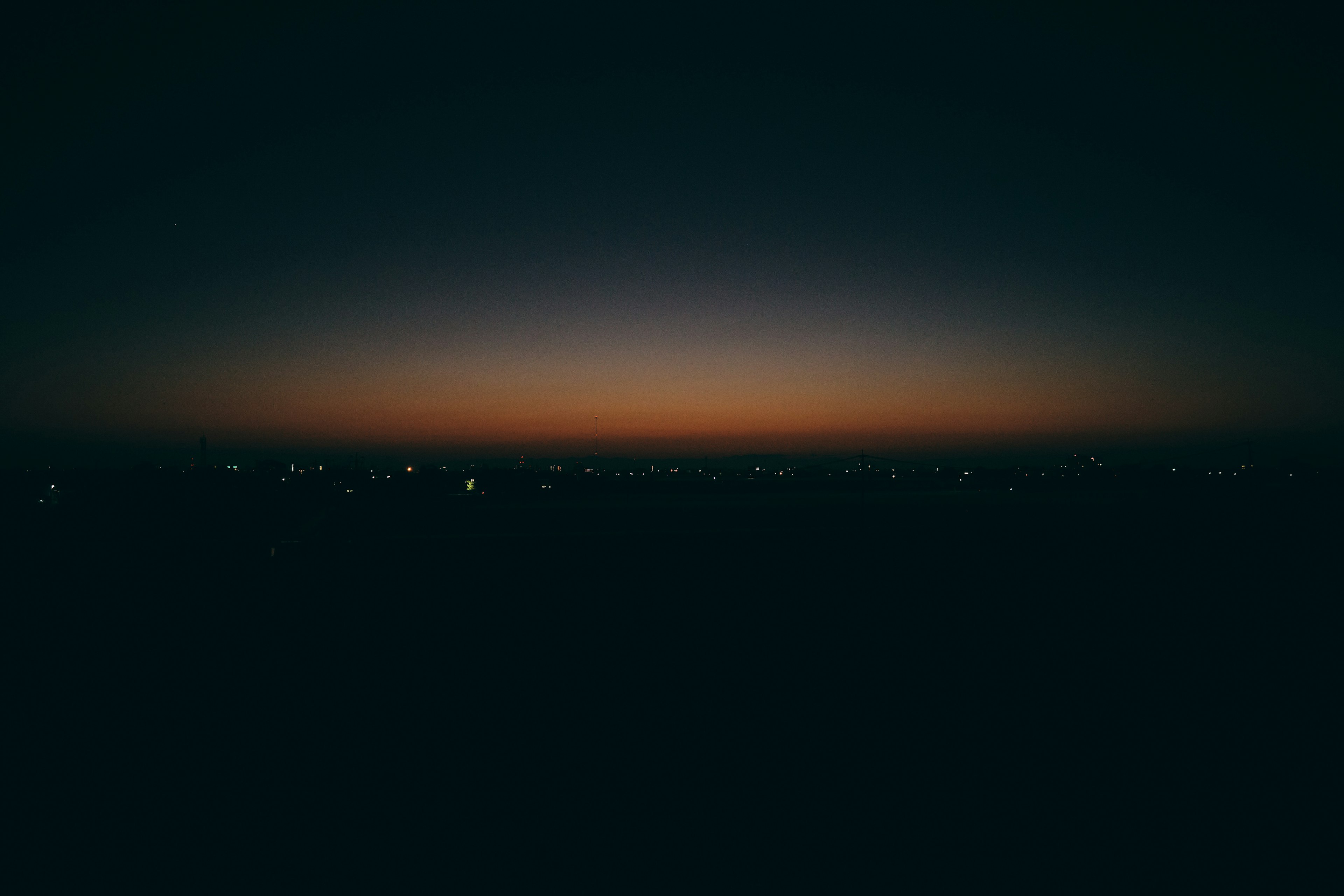 Ciel crépusculaire avec un horizon sombre et des lumières de ville au loin