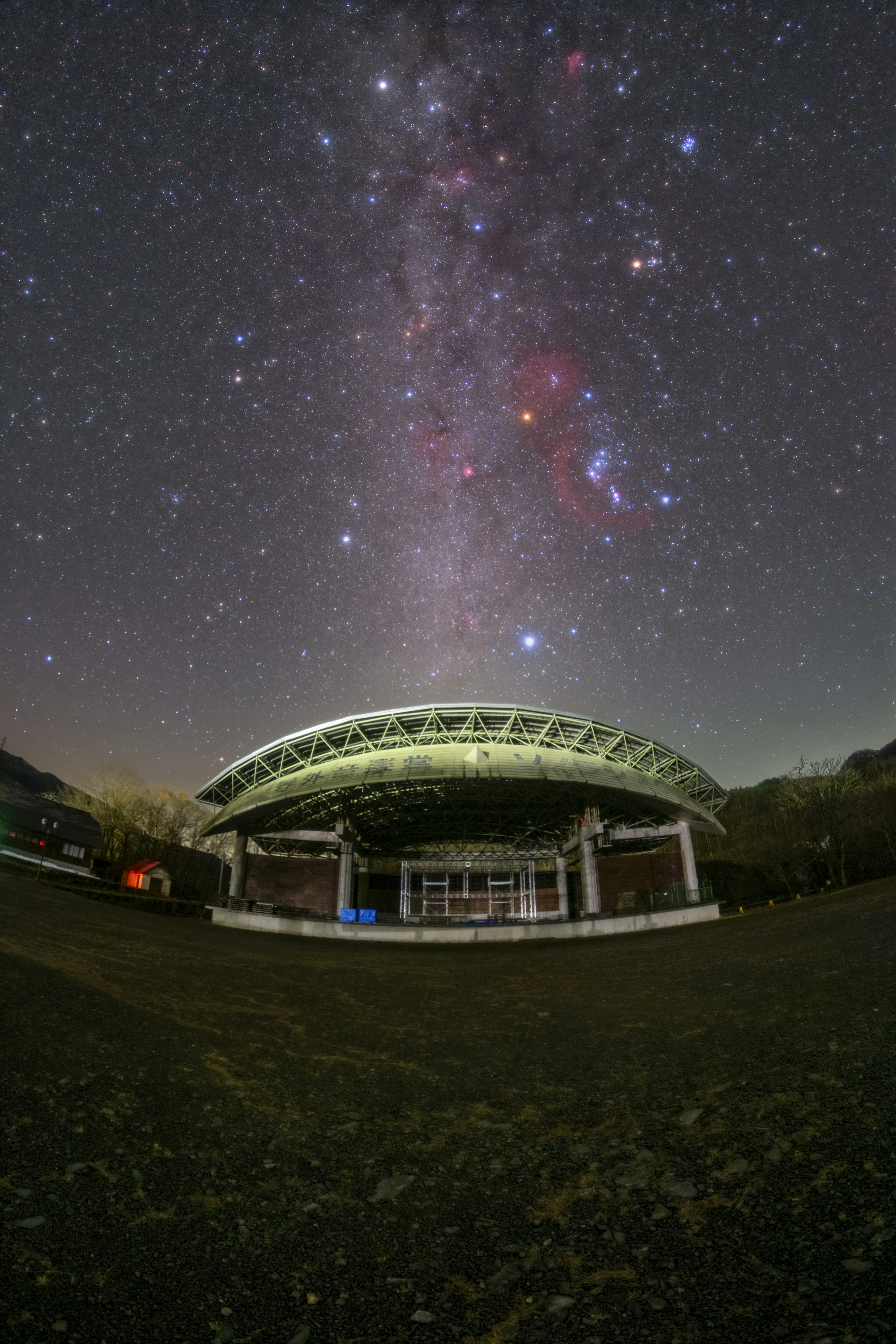 星空の下にある大きな屋根のある建物と銀河の美しい景色