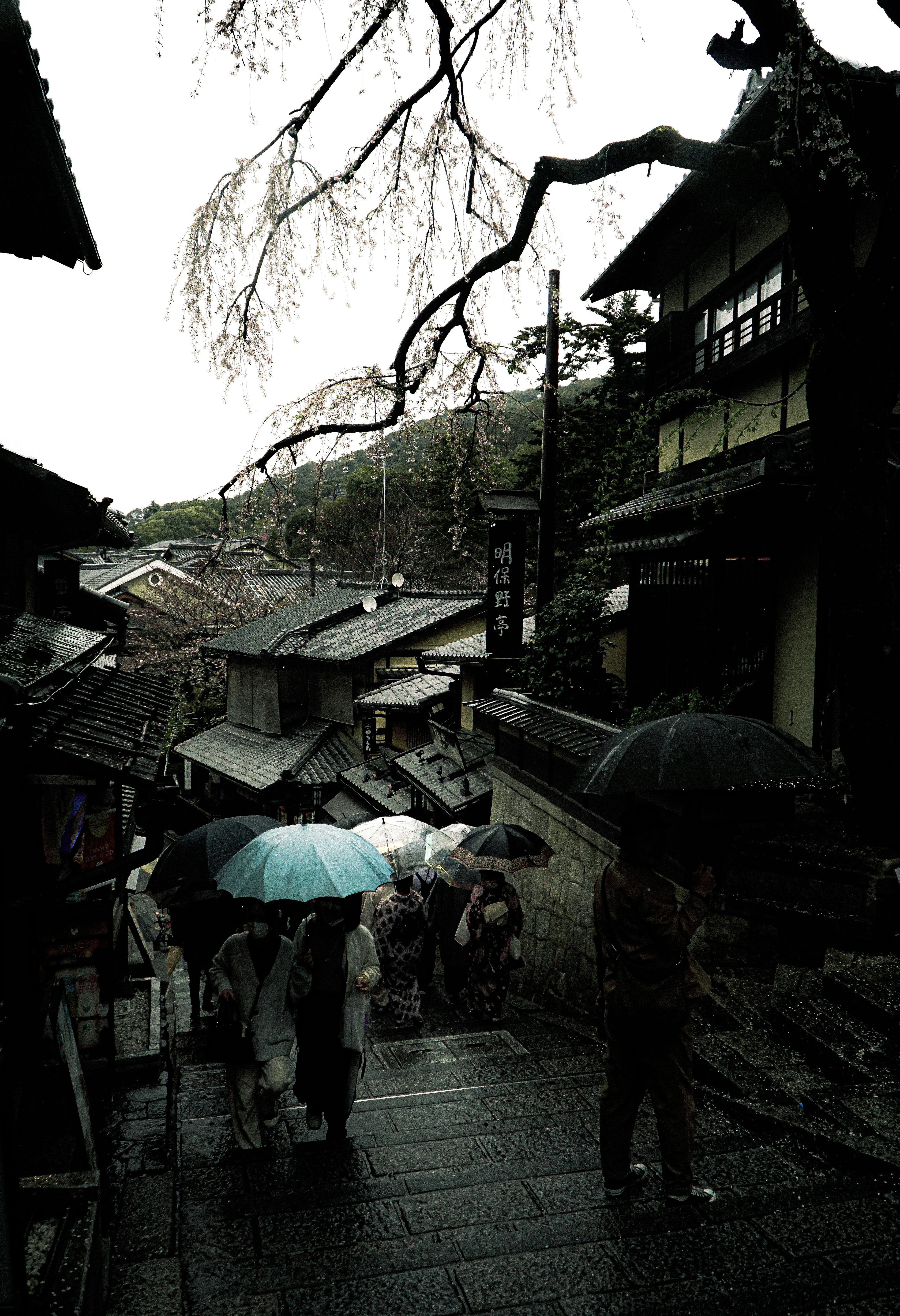 雨の日の古い街並みで傘を持った人々が歩いている