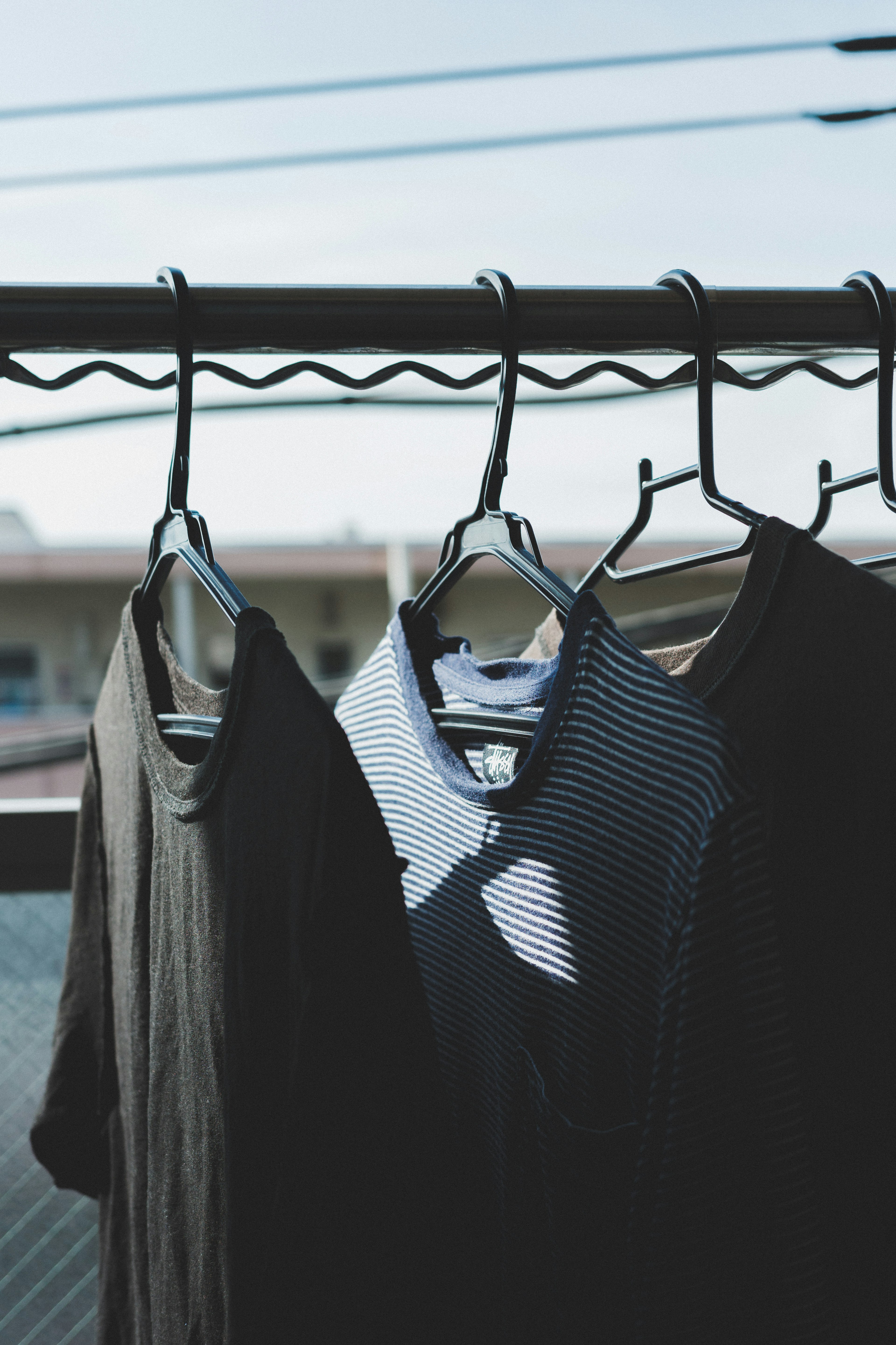 Clothes hanging on a rack black shirts and striped shirt