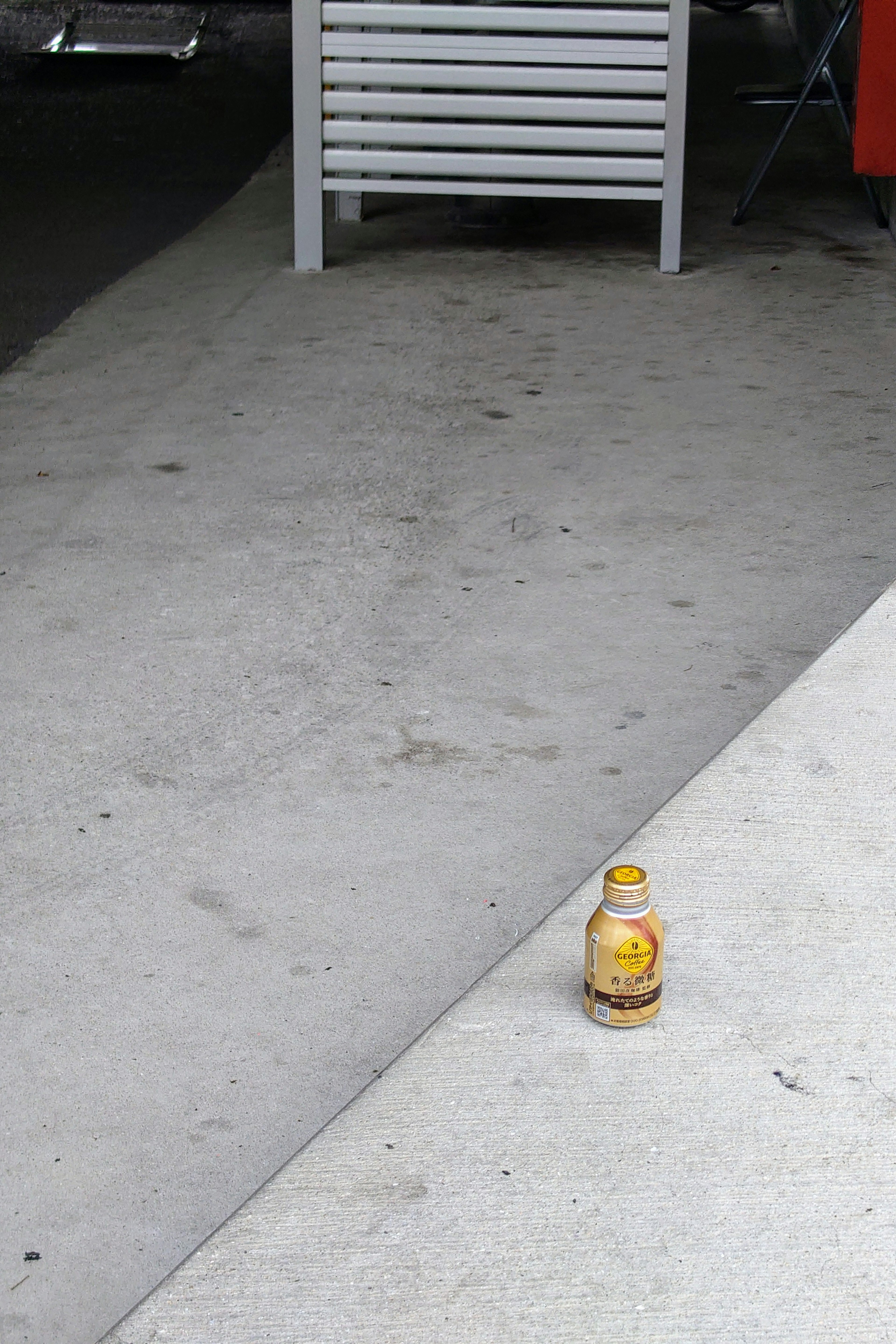 Gelbe Getränkeflasche auf einer Betonfläche mit der umliegenden Umgebung