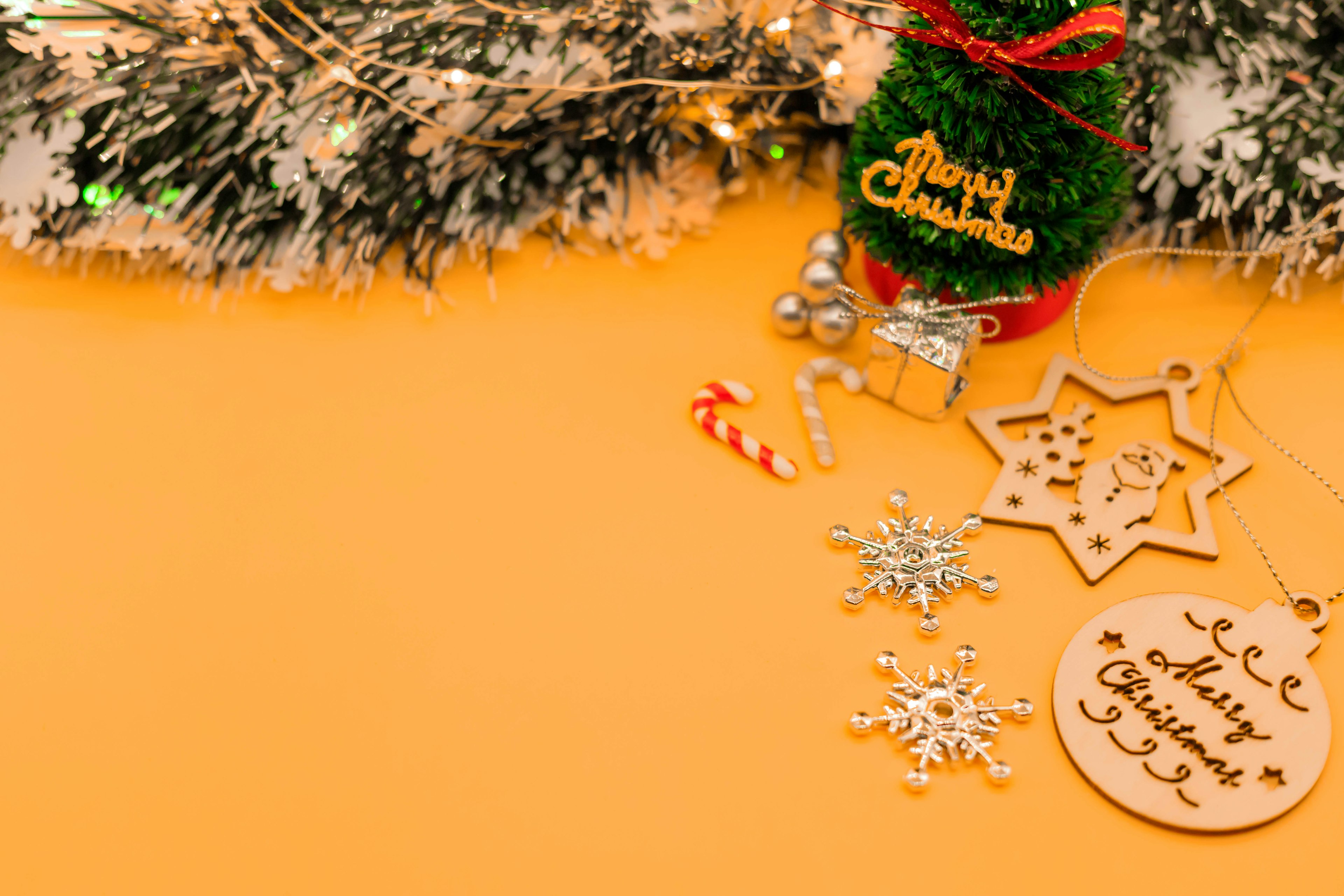 Weihnachtsdekorationen einschließlich eines kleinen Baumes und Ornamenten auf einem gelben Hintergrund