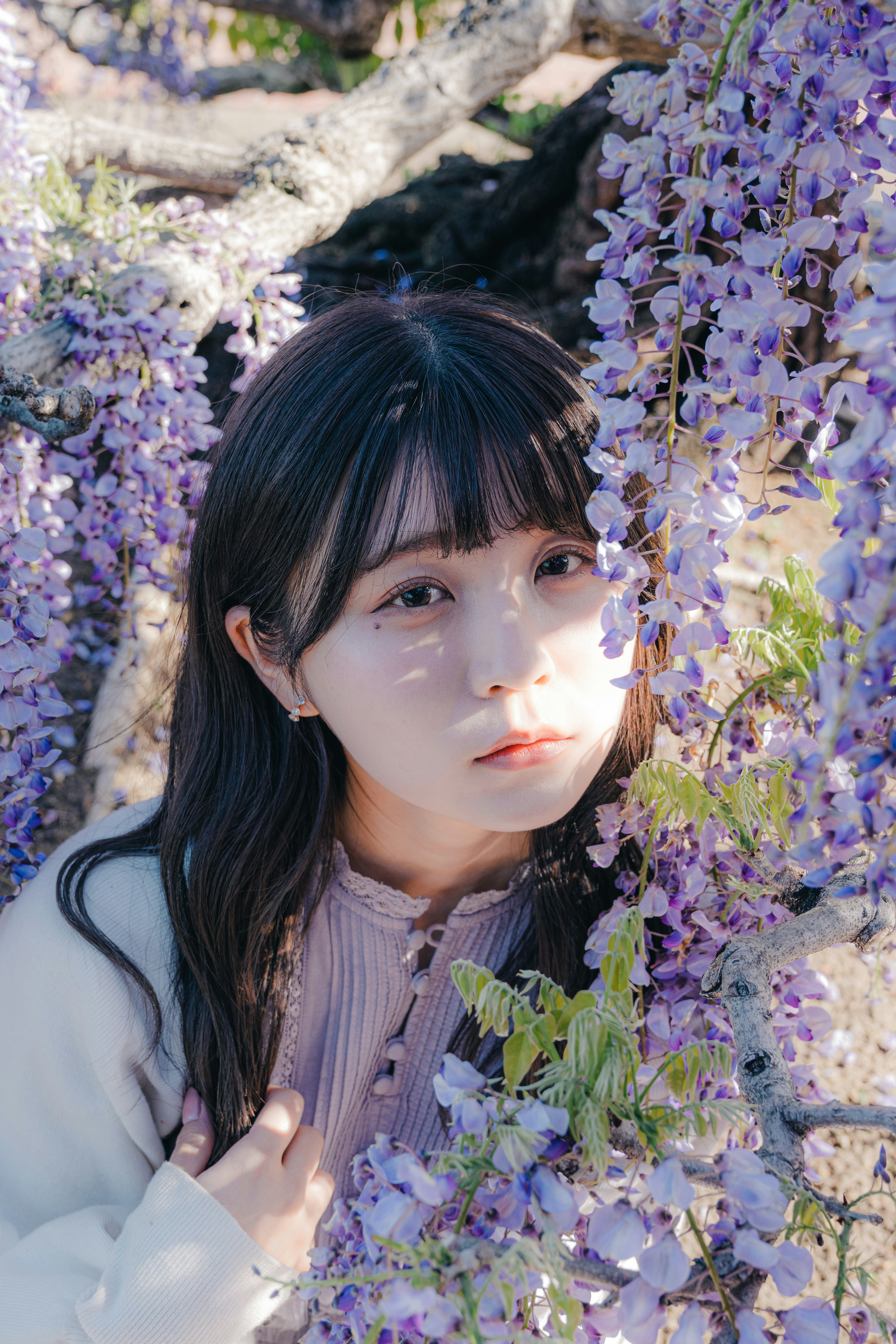 Portrait of a woman smiling in front of purple wisteria flowers