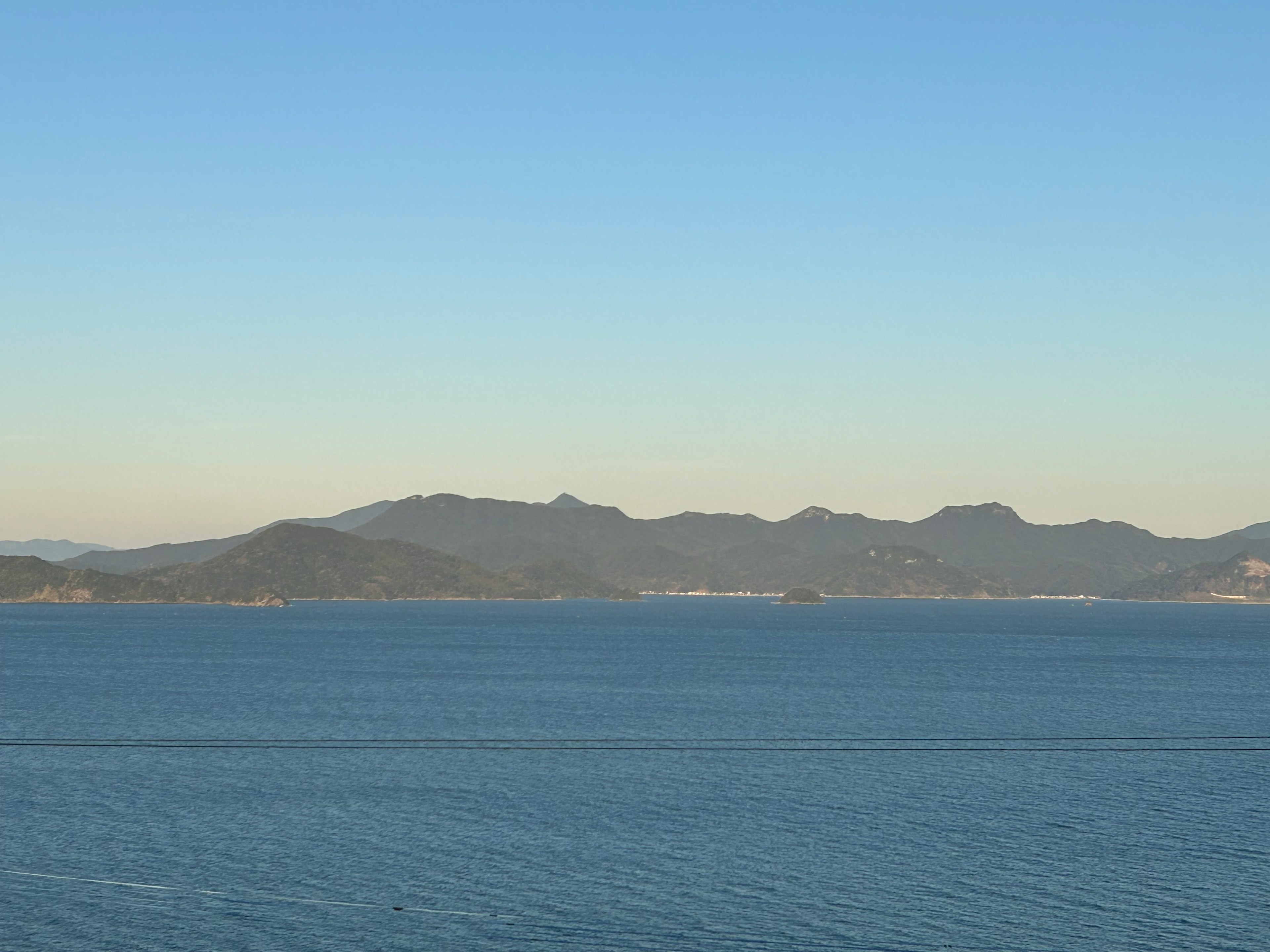 Serene sea and mountain landscape clear blue sky and calm water surface