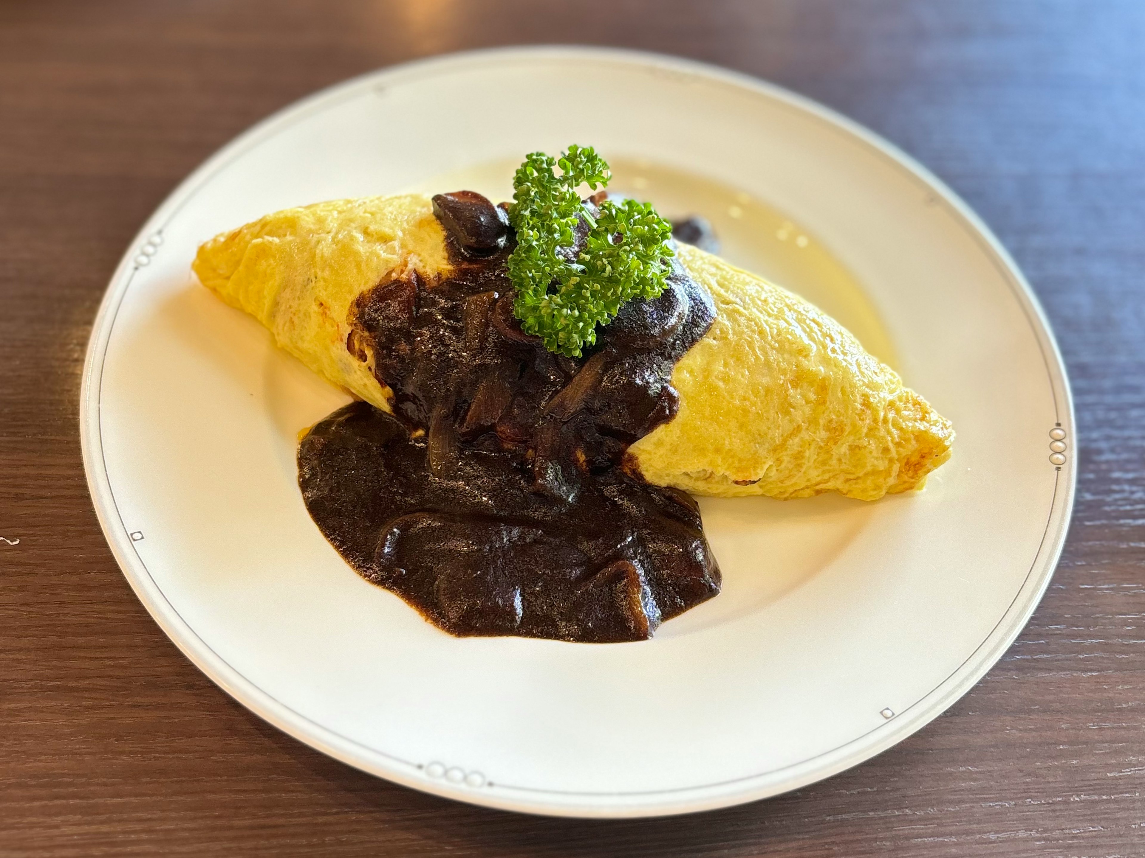 Plato de arroz omelette cubierto con salsa negra omelette amarilla y adorno de perejil