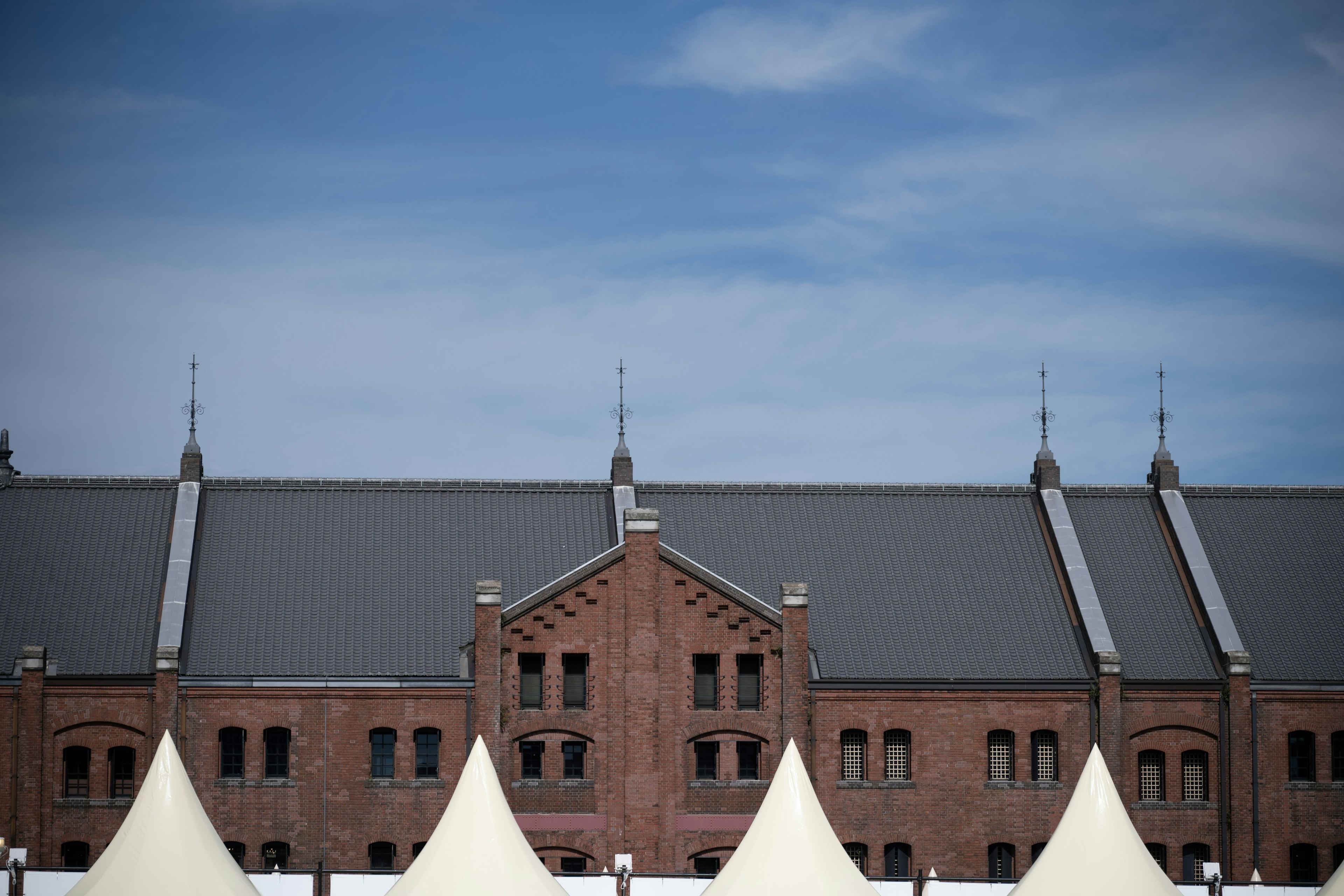 Rotes Backsteingebäude unter blauem Himmel mit weißen Zelten im Vordergrund