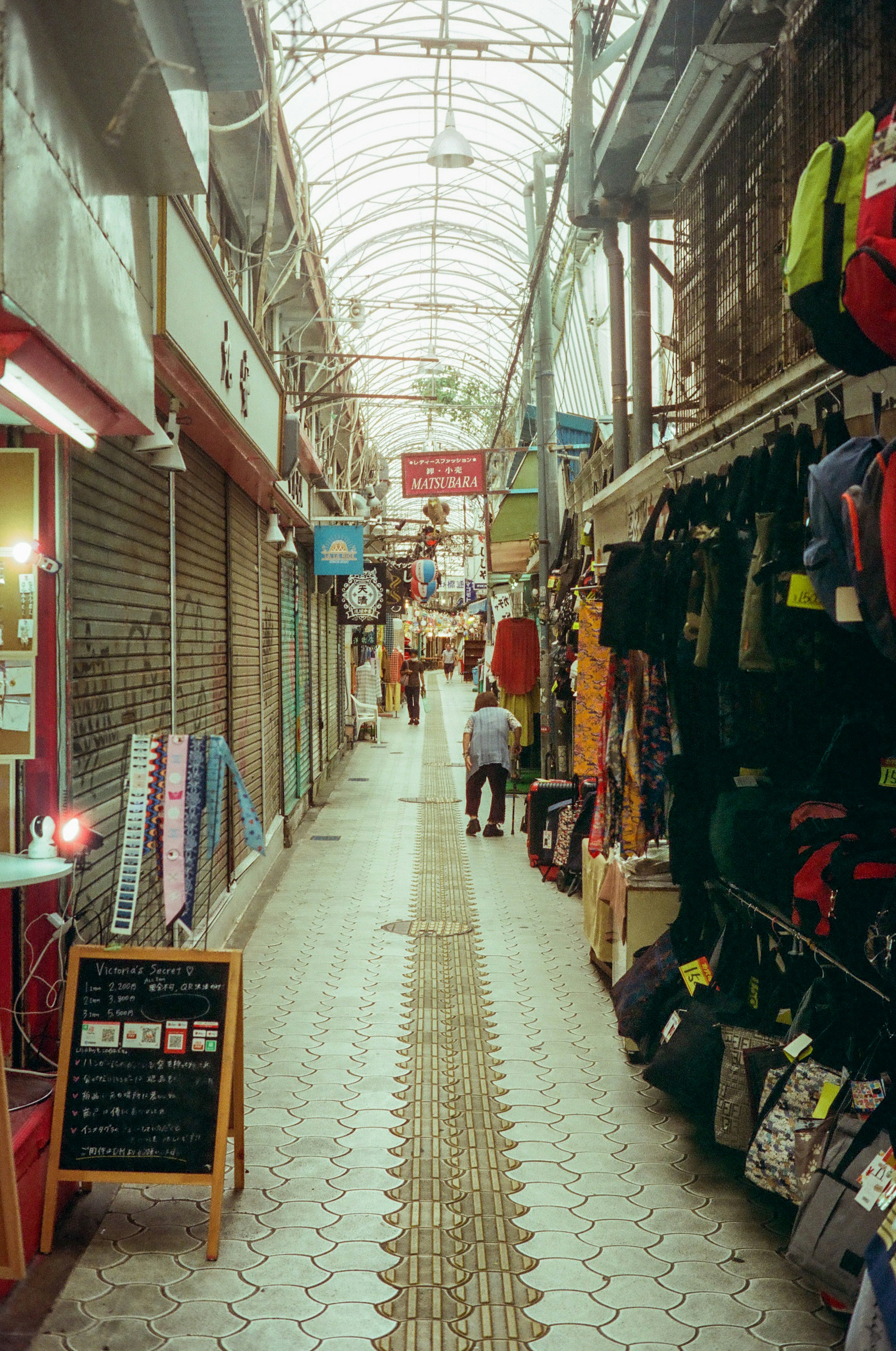 Narrow shopping alley lined with colorful backpacks and merchandise