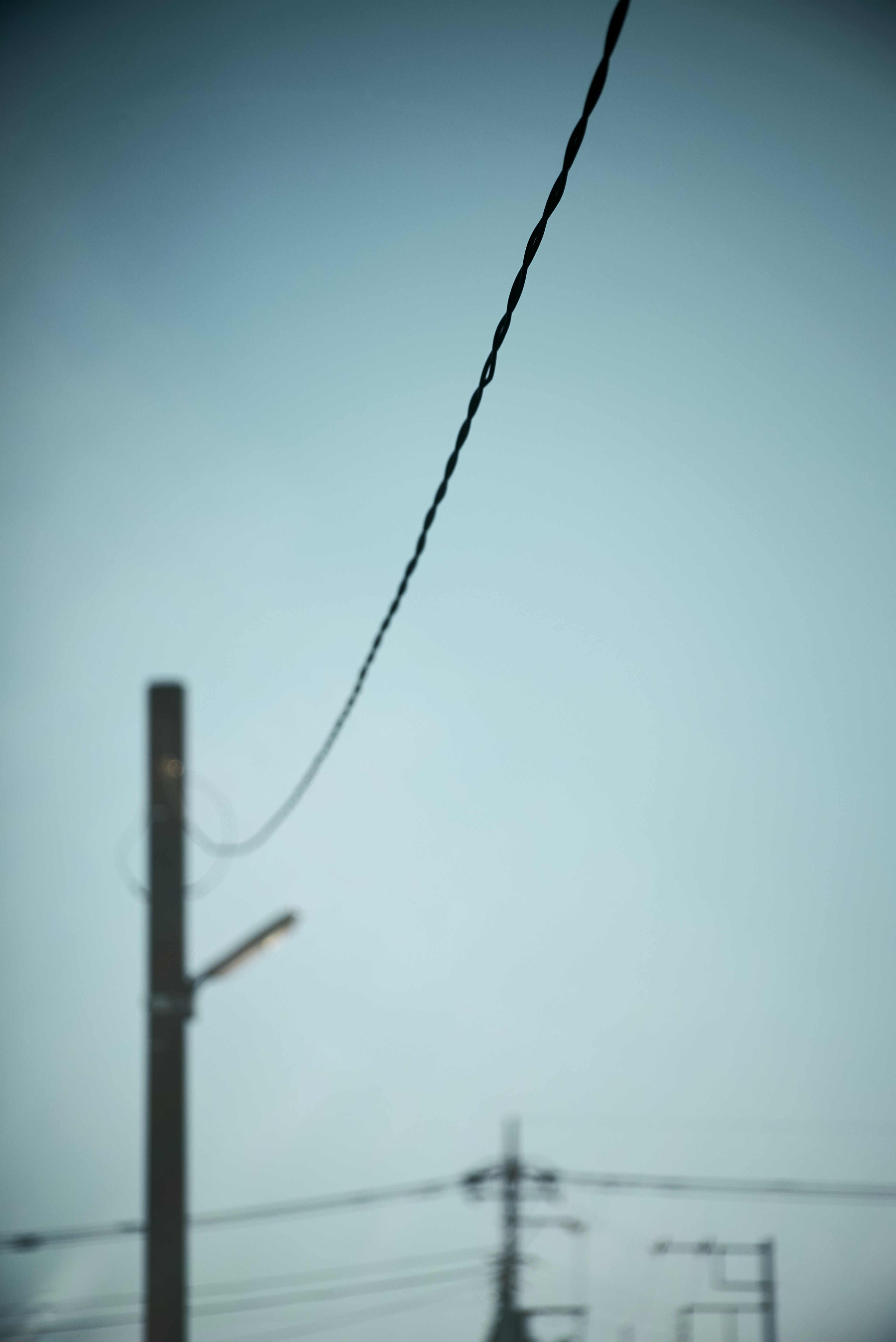 Close-up of a utility pole and power line against a blue sky