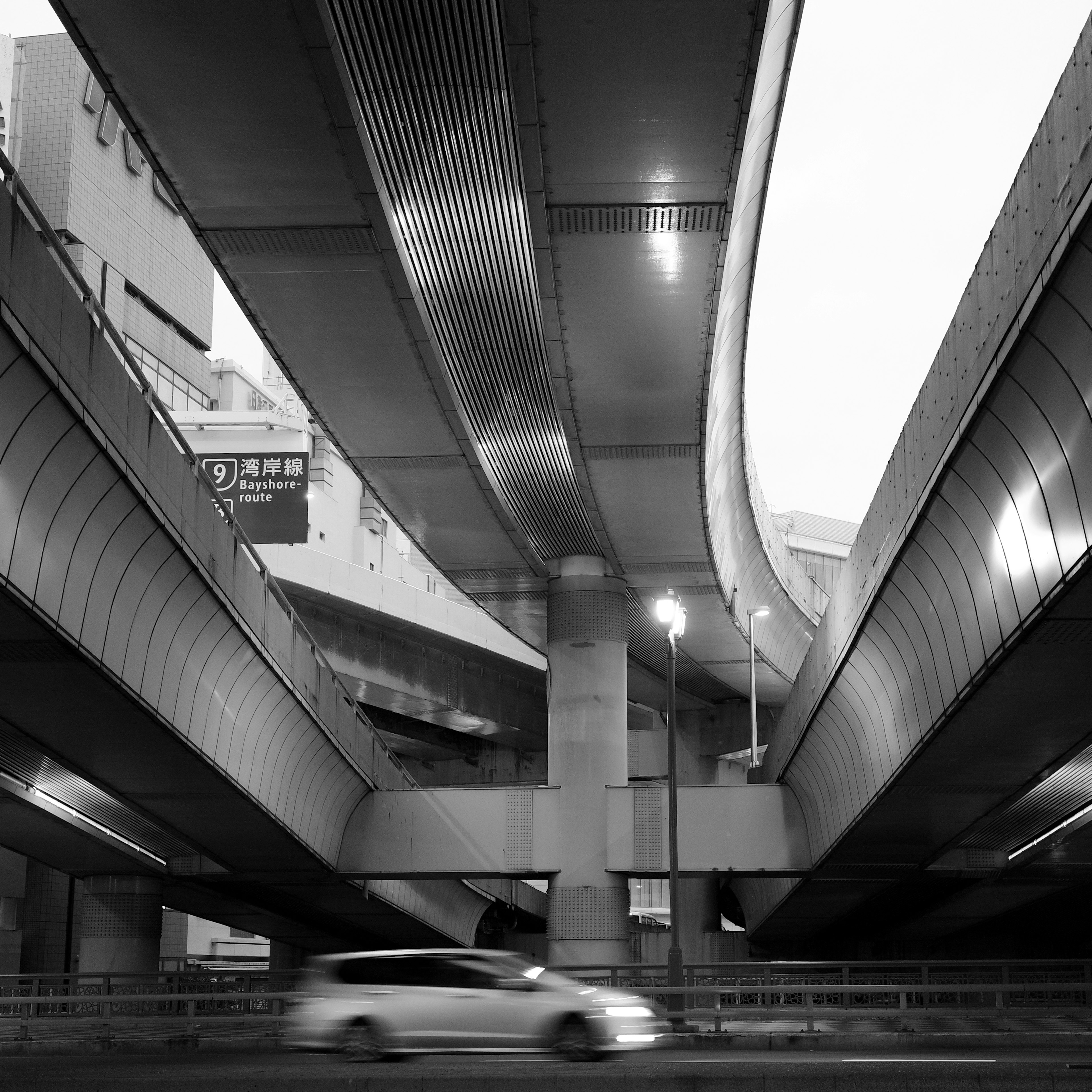 Escena urbana en blanco y negro con autopistas curvas y estructuras que se cruzan