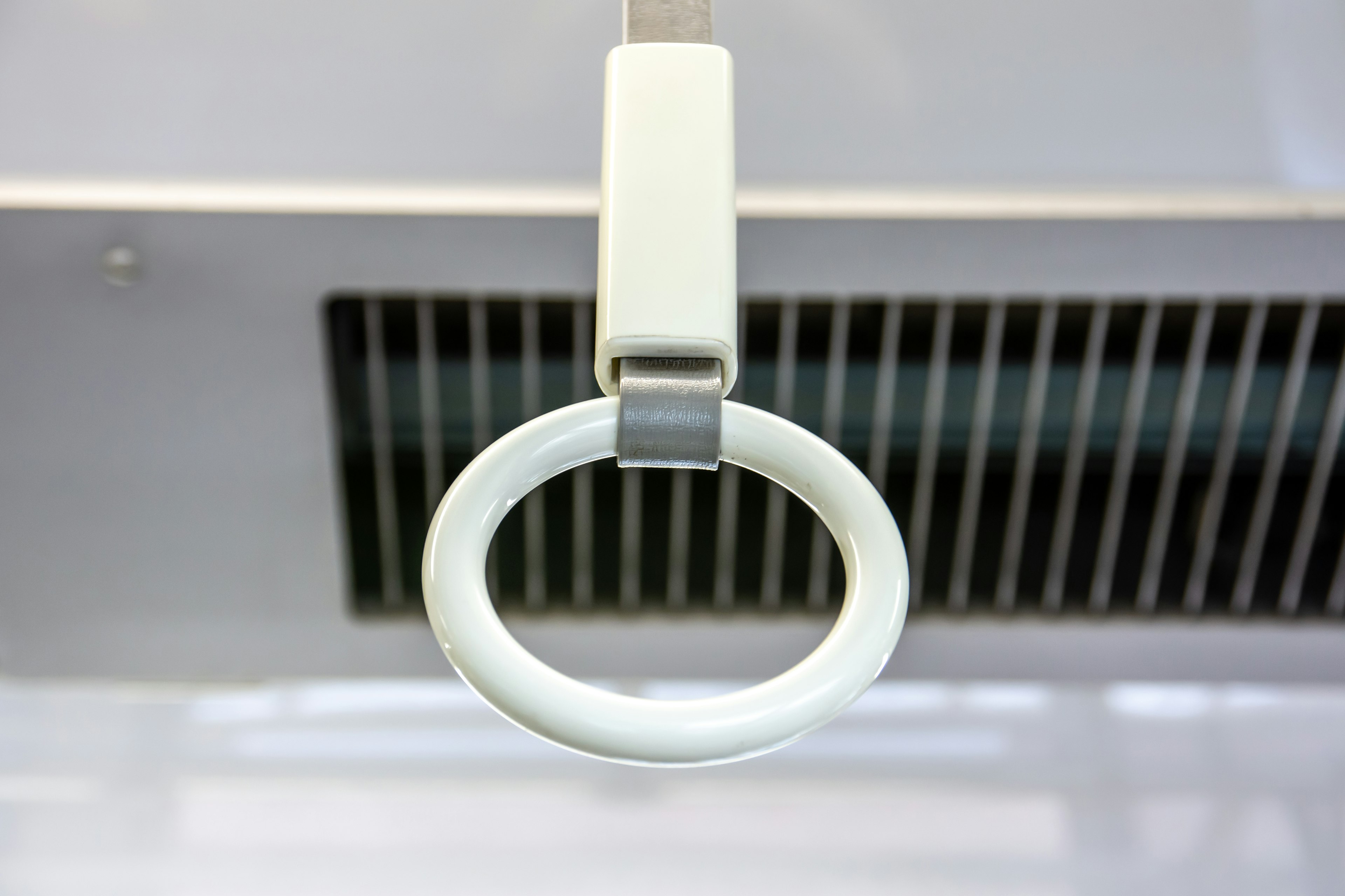 Close-up of a white subway hand strap in a train interior