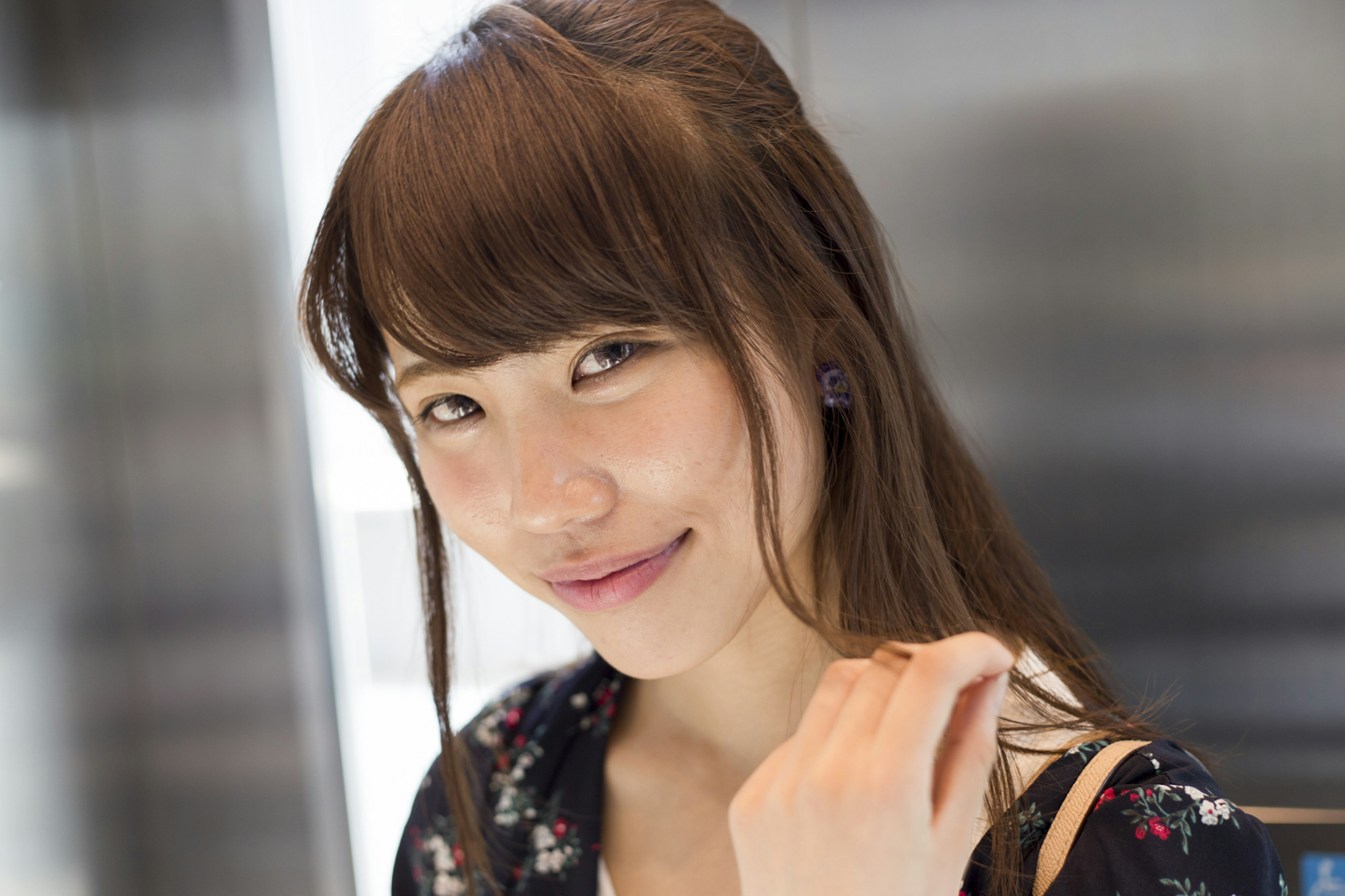 Portrait of a smiling woman in an elevator with long brown hair wearing a floral dress