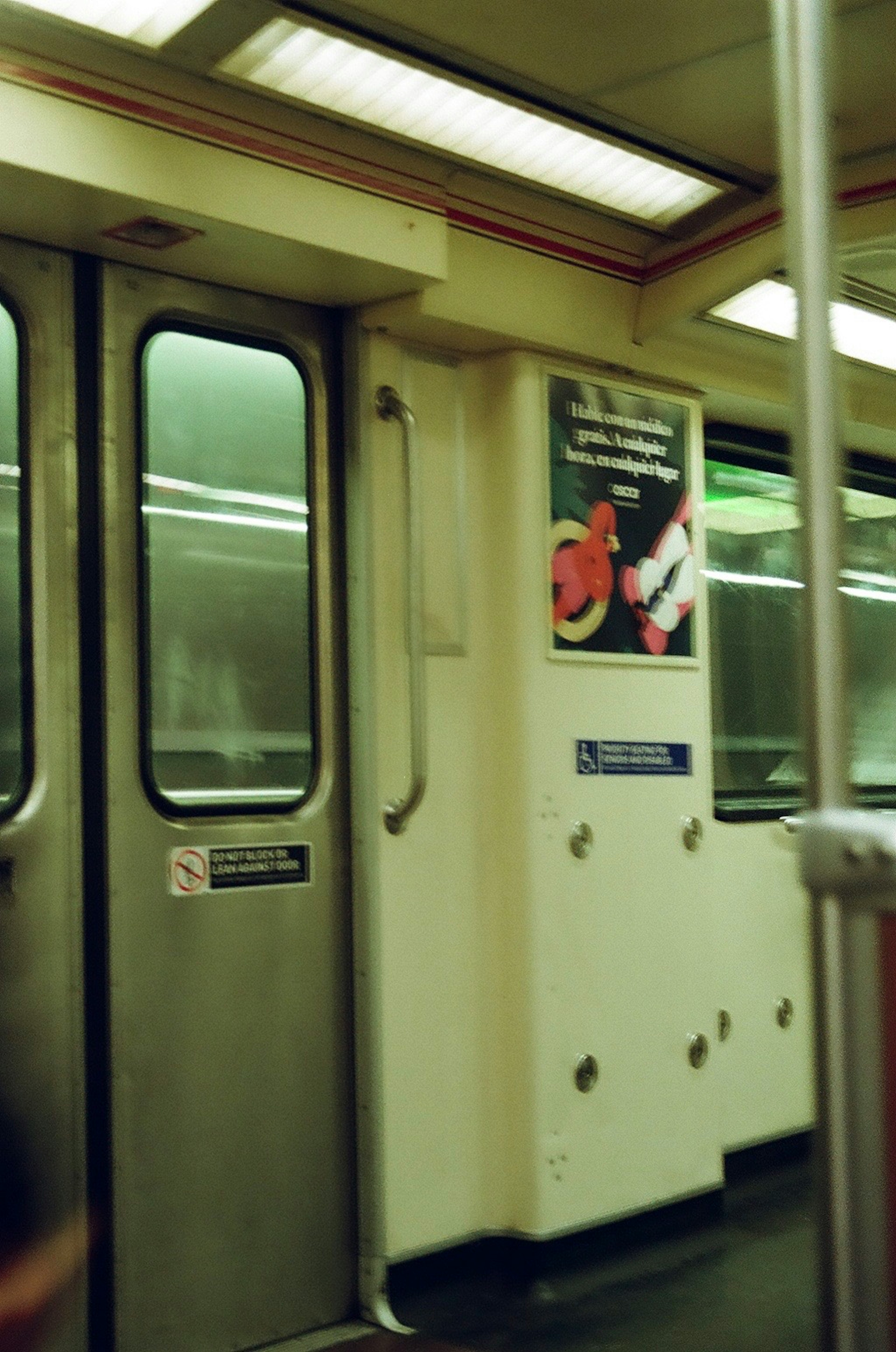 Interior de un vagón de metro con puertas y un anuncio en la pared