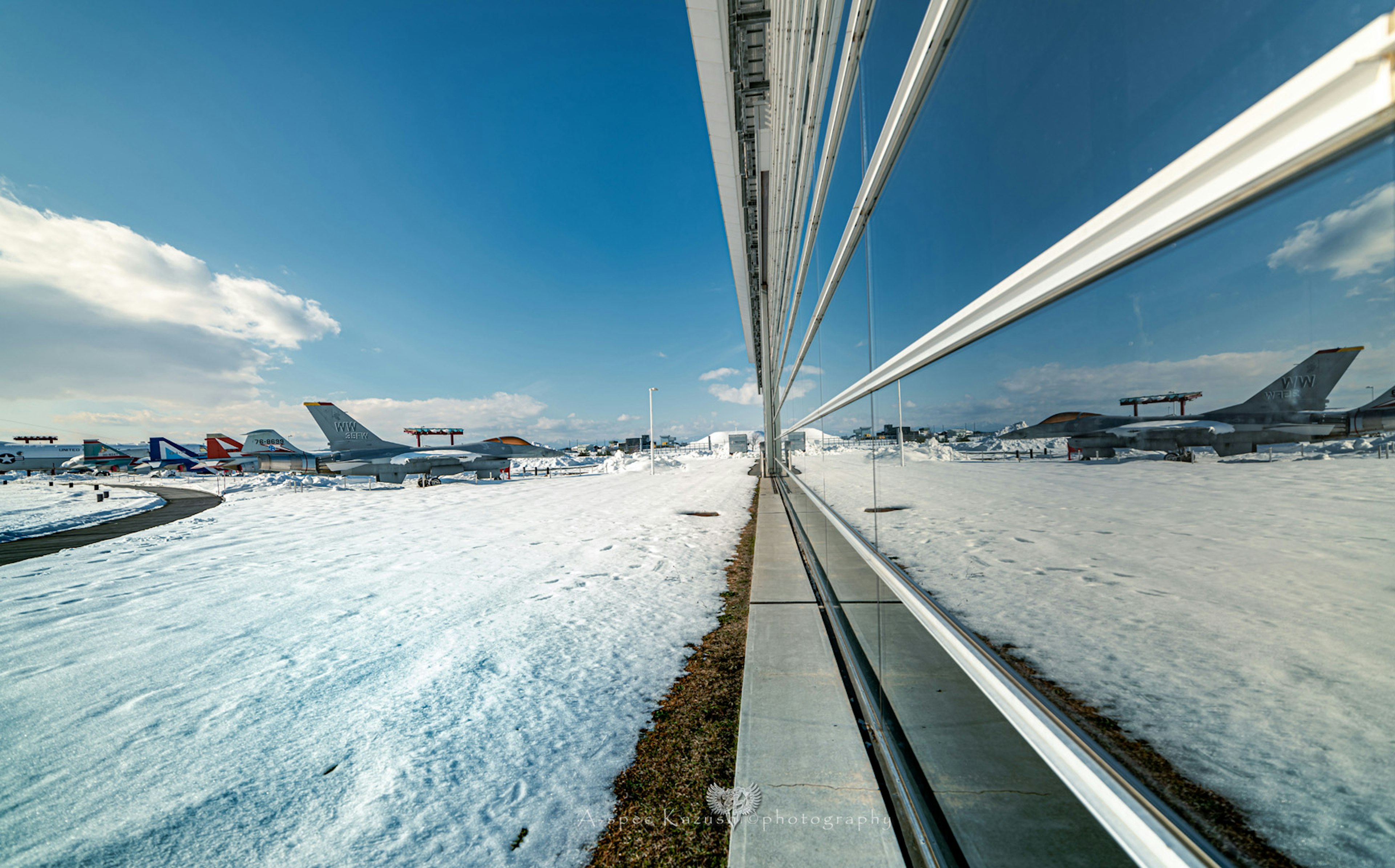 雪に覆われた空港の滑走路と航空機の反射が映るガラス