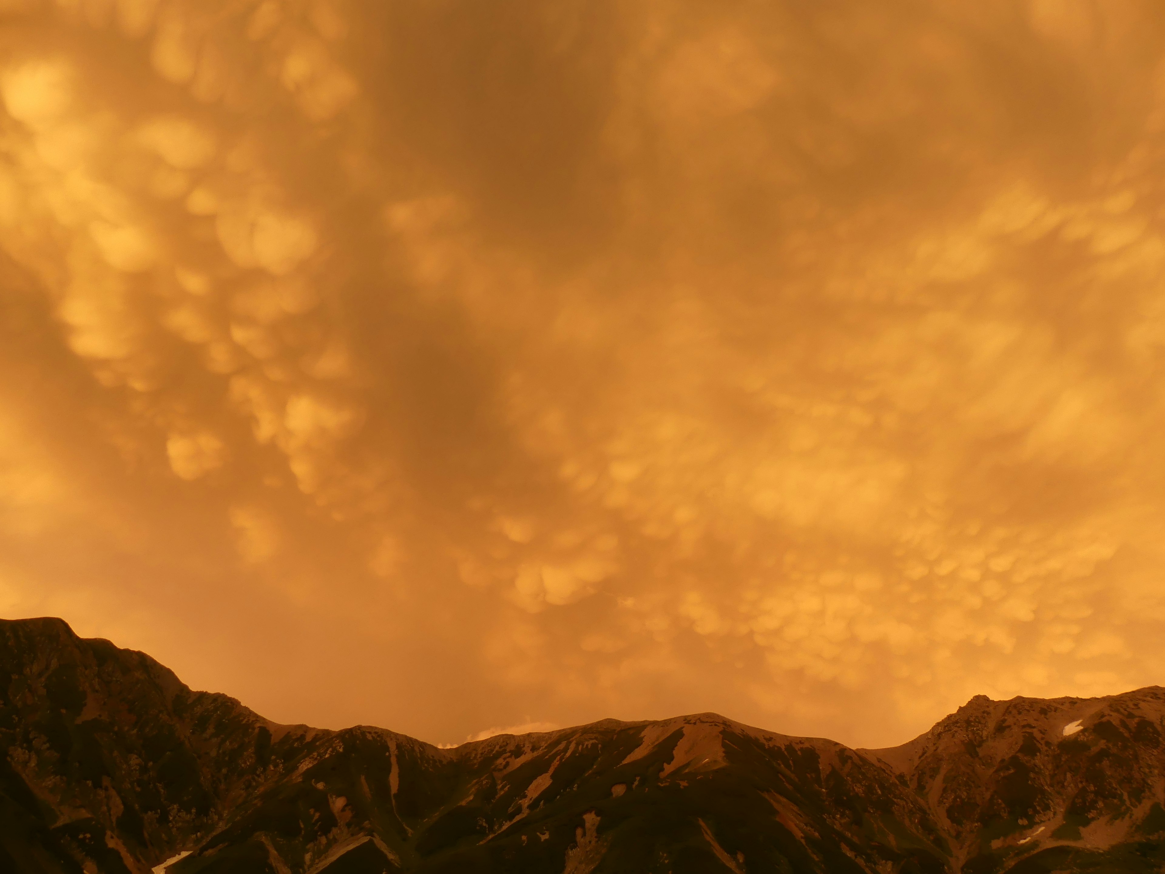 Cadena montañosa bajo un cielo naranja al atardecer