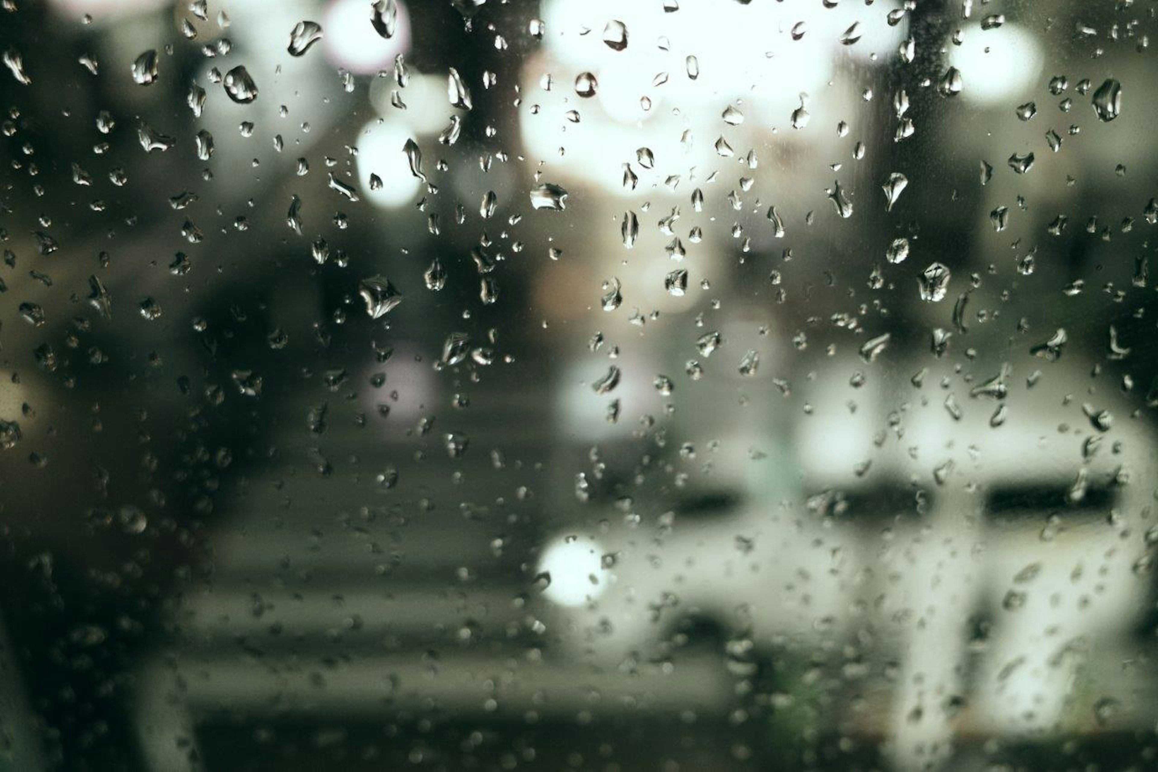 雨滴が付いた窓越しに見えるぼやけた街の風景