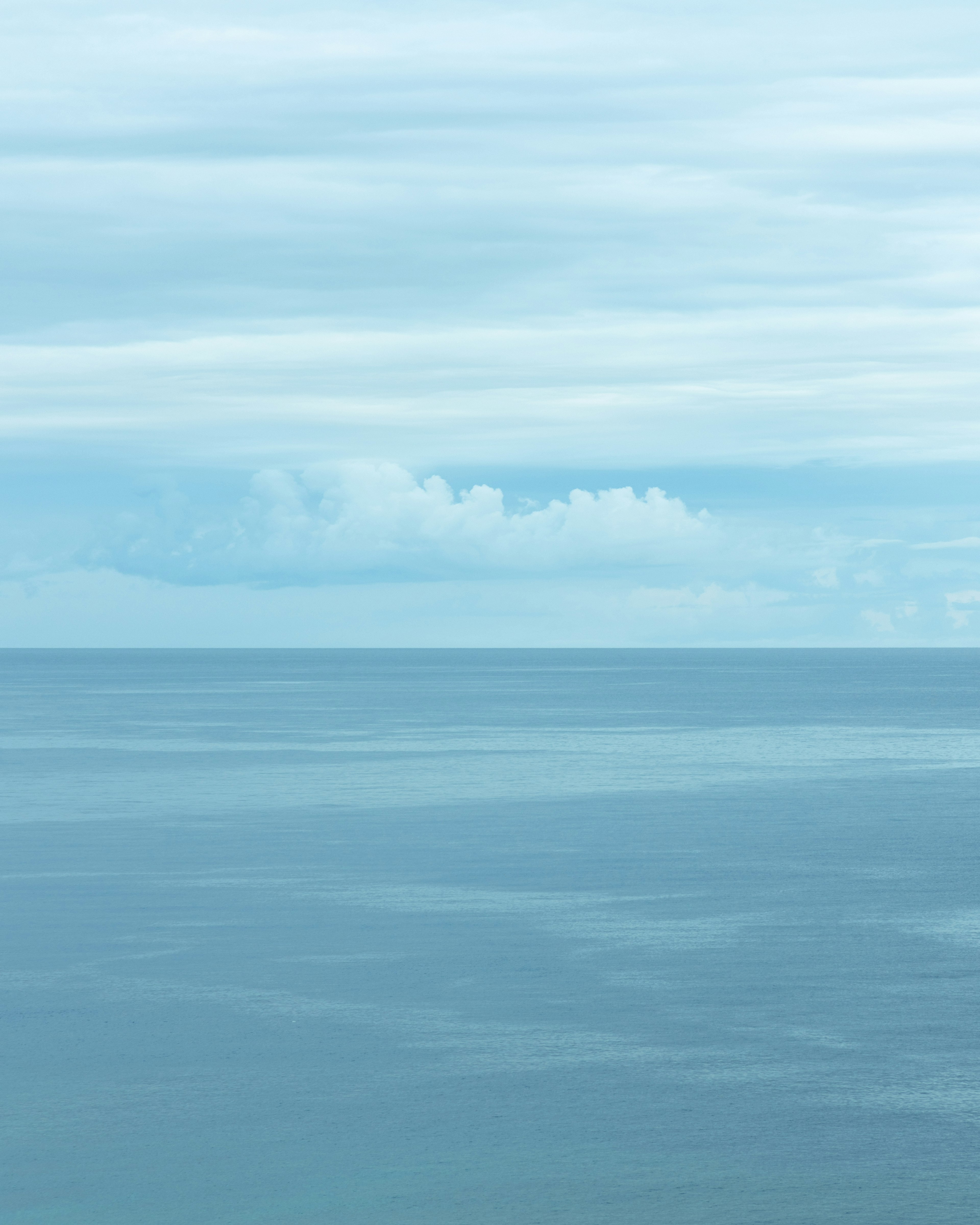 Laut biru tenang dan awan di langit