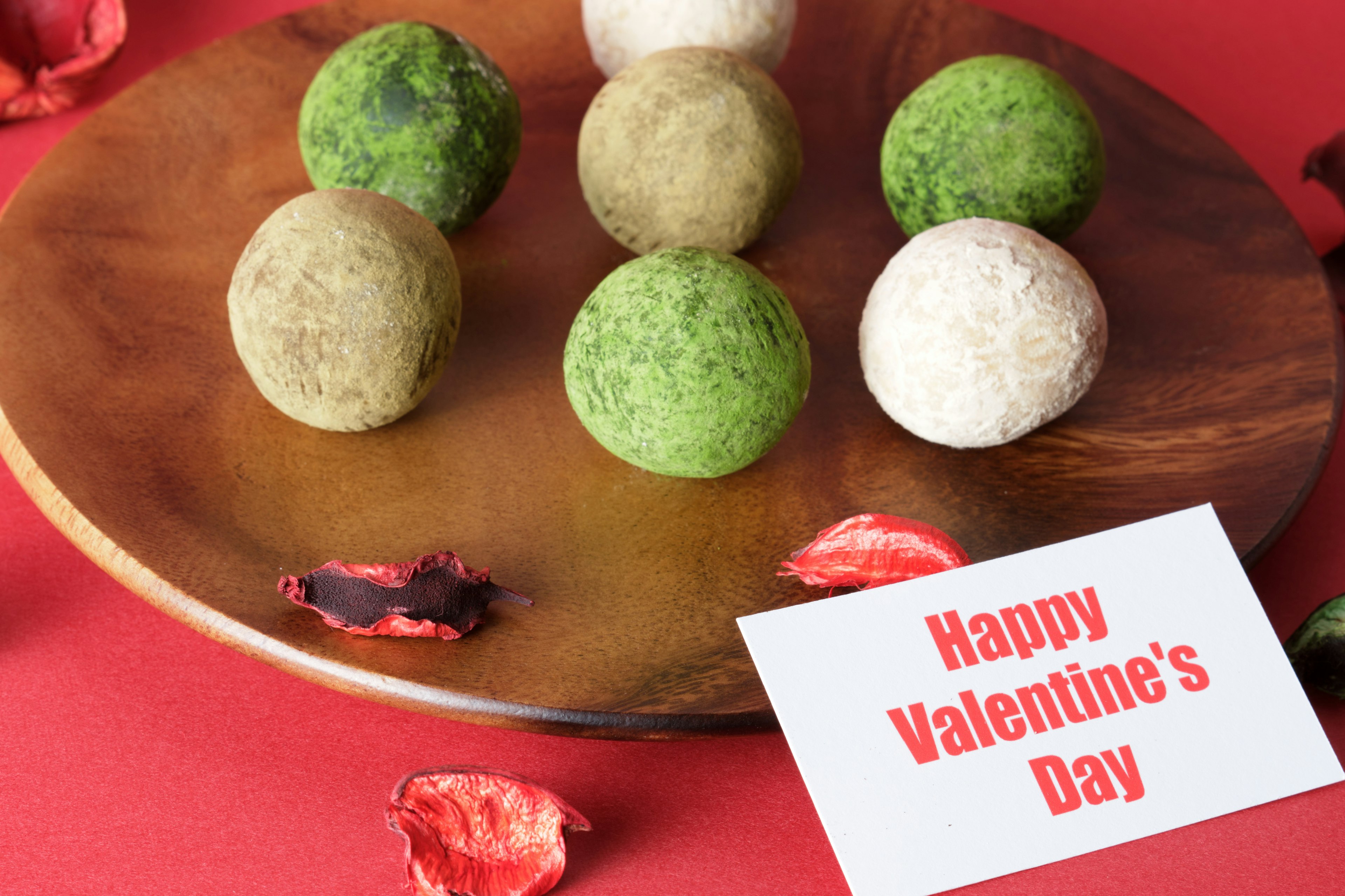 Colorful balls arranged on a wooden plate with a card saying Happy Valentine's Day