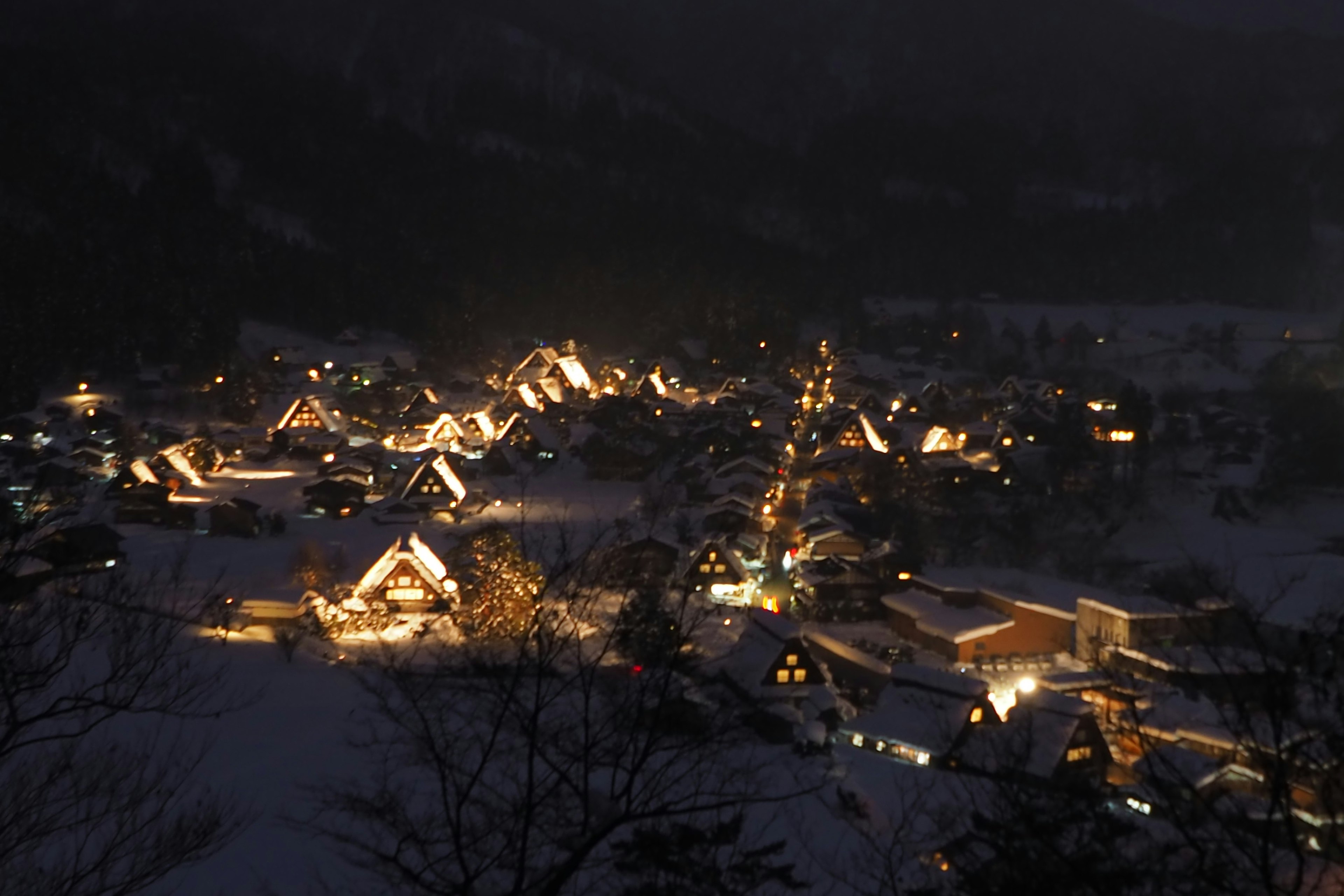 Vista notturna di un villaggio coperto di neve con case illuminate