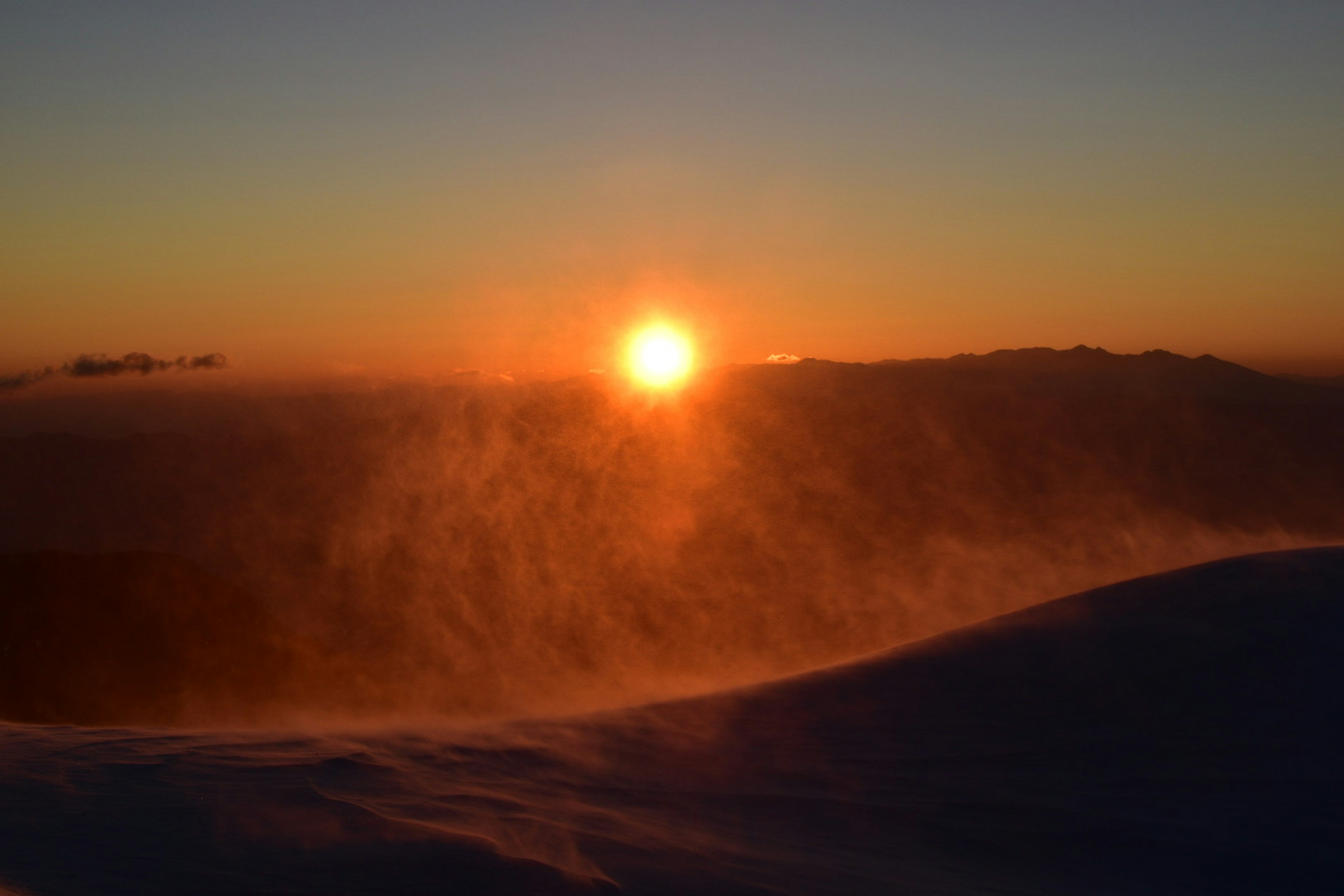 Magnifique coucher de soleil sur des collines enneigées avec une lueur chaude