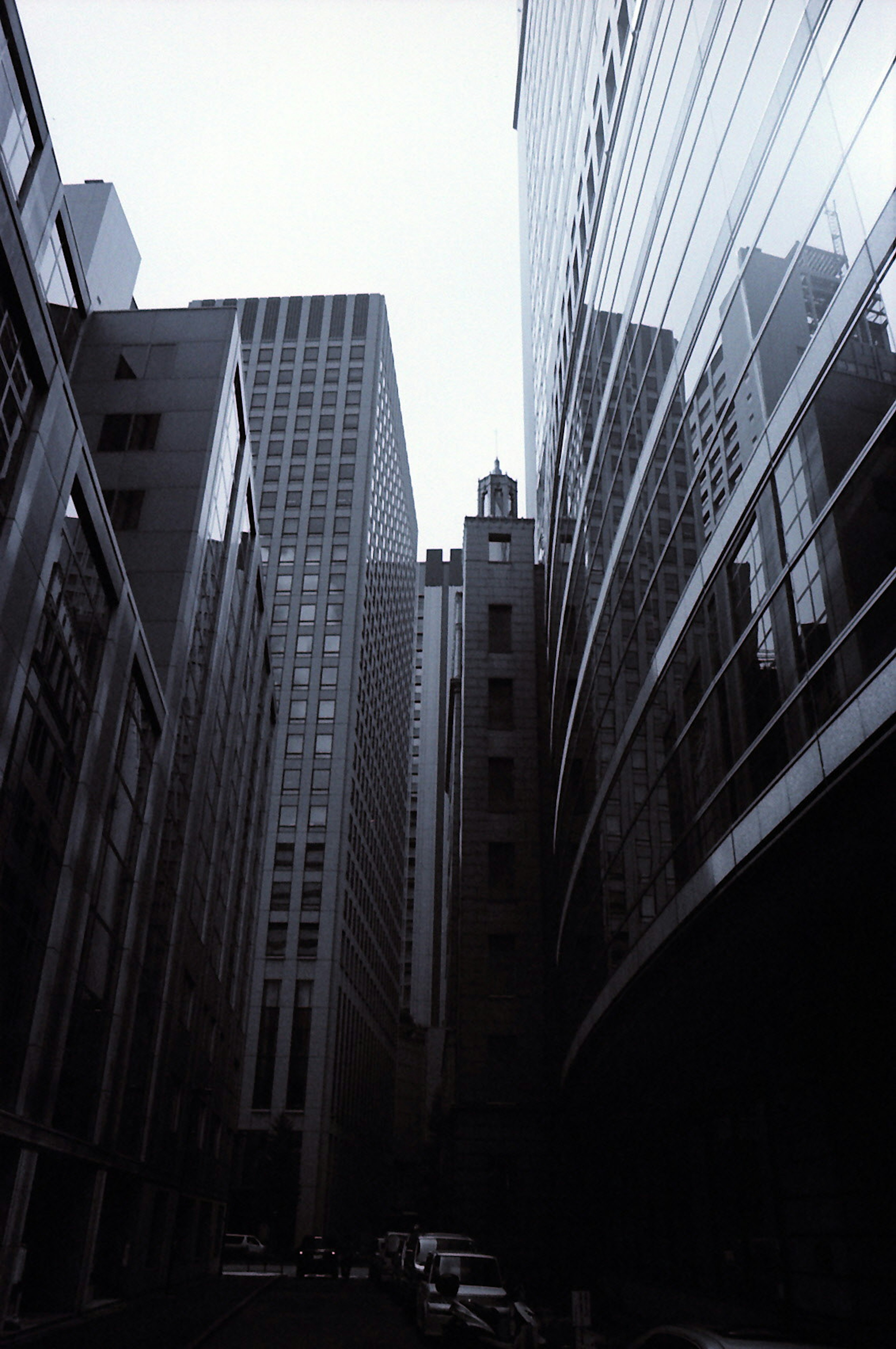 Monochrome photo of a narrow street between tall buildings