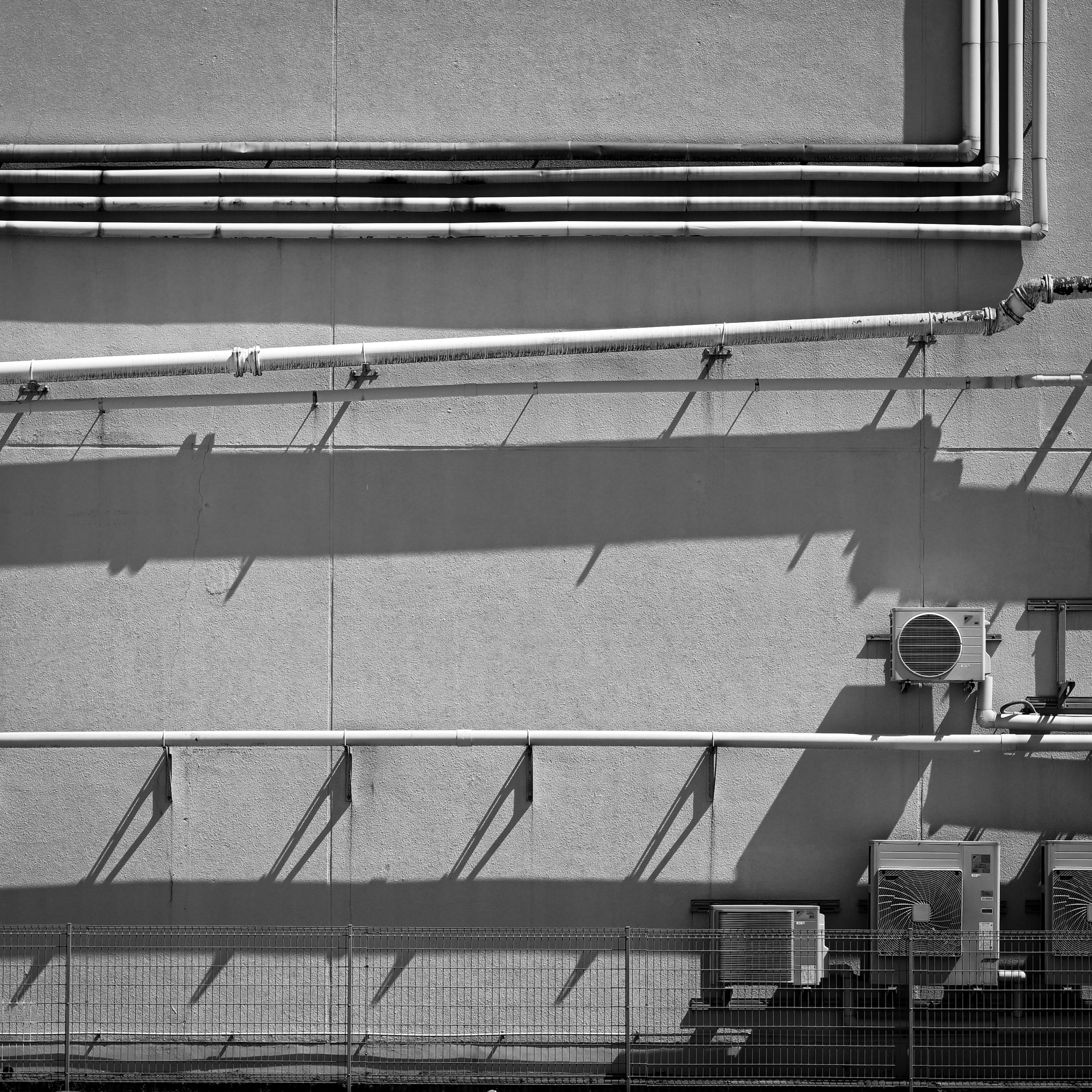 Contraste des tuyaux et des ombres sur un mur de bâtiment en noir et blanc