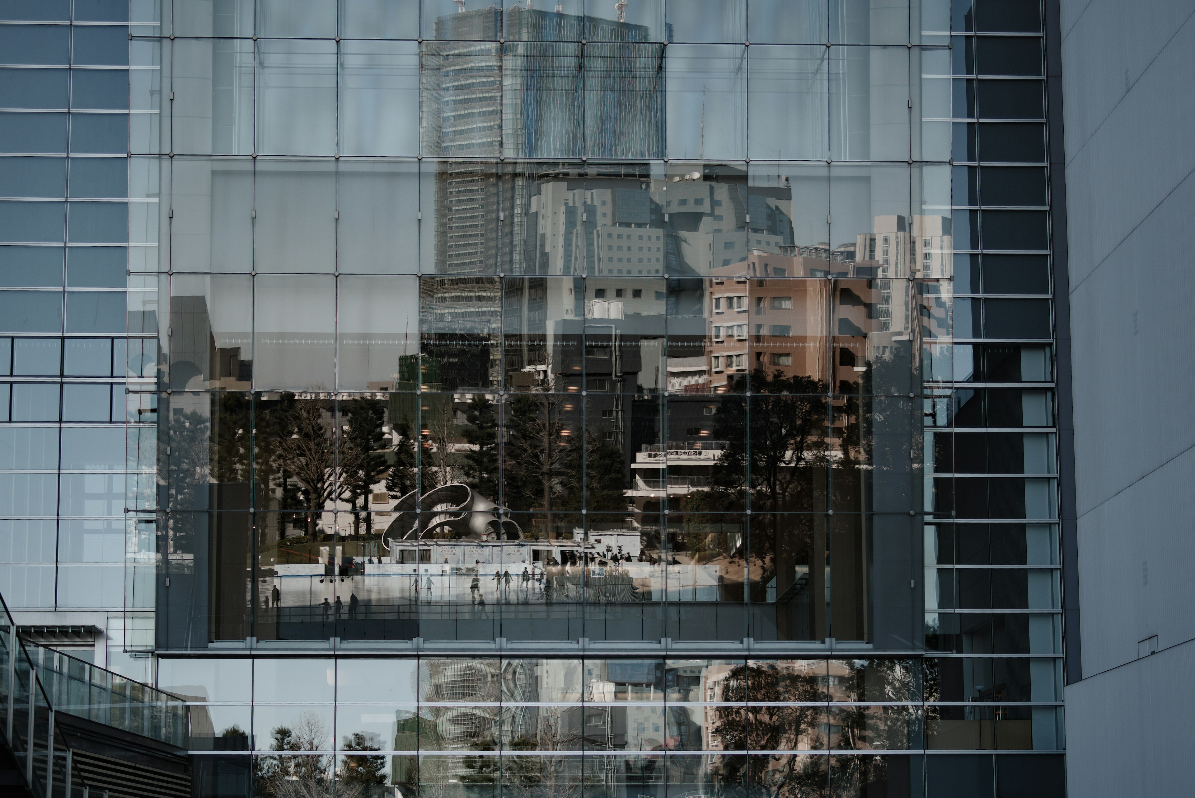 Reflejo de un edificio moderno en vidrio que muestra el paisaje urbano y la vegetación