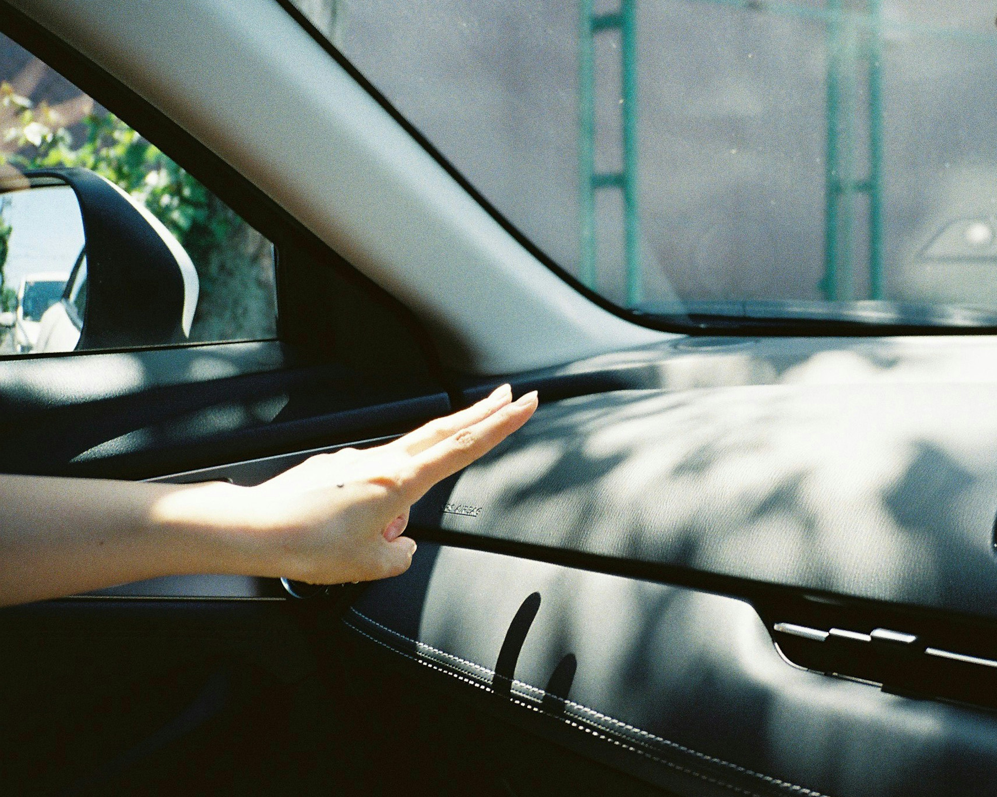 Hand hovering over a car dashboard with soft sunlight