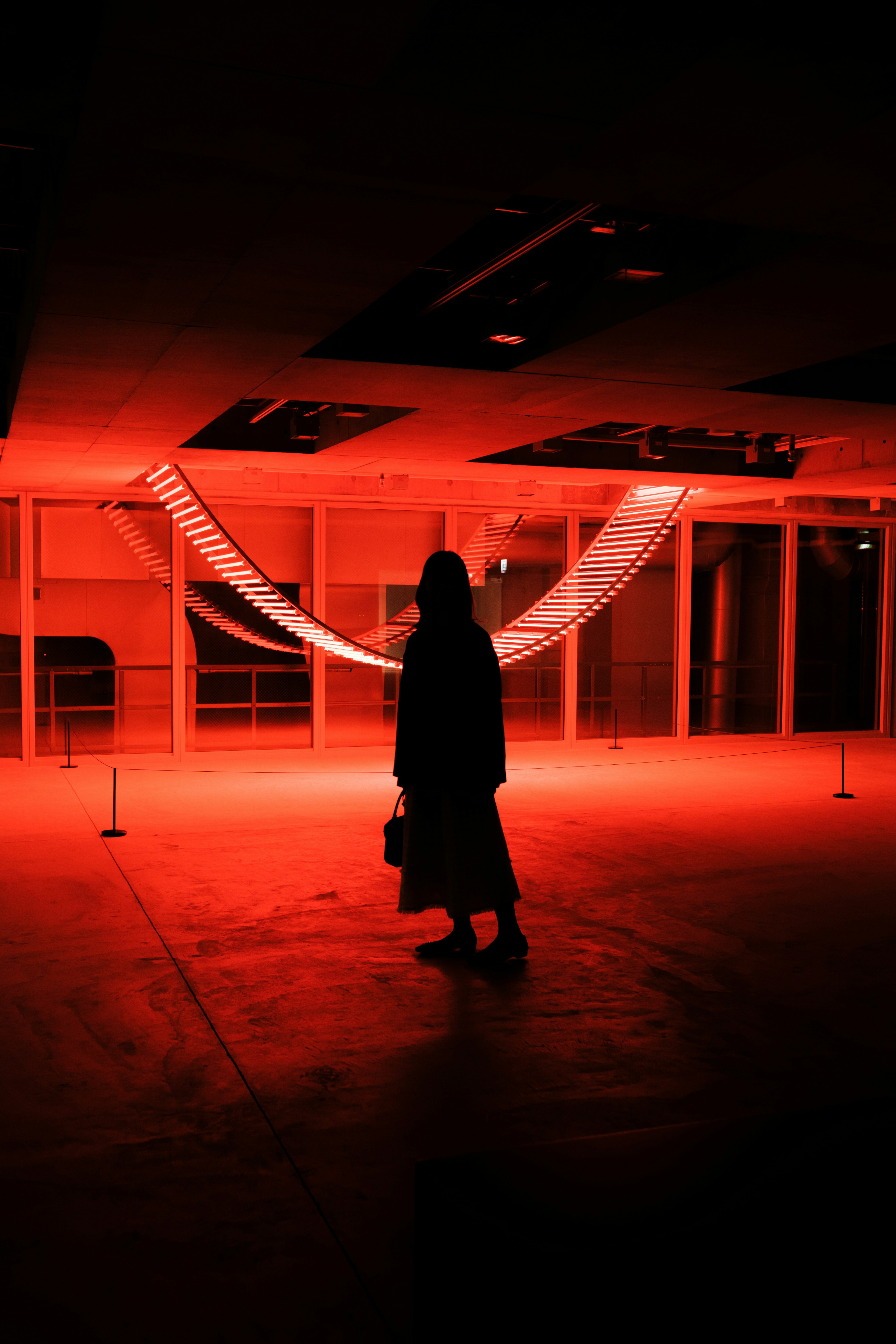 Silhouette of a woman standing in red light with a lighting installation