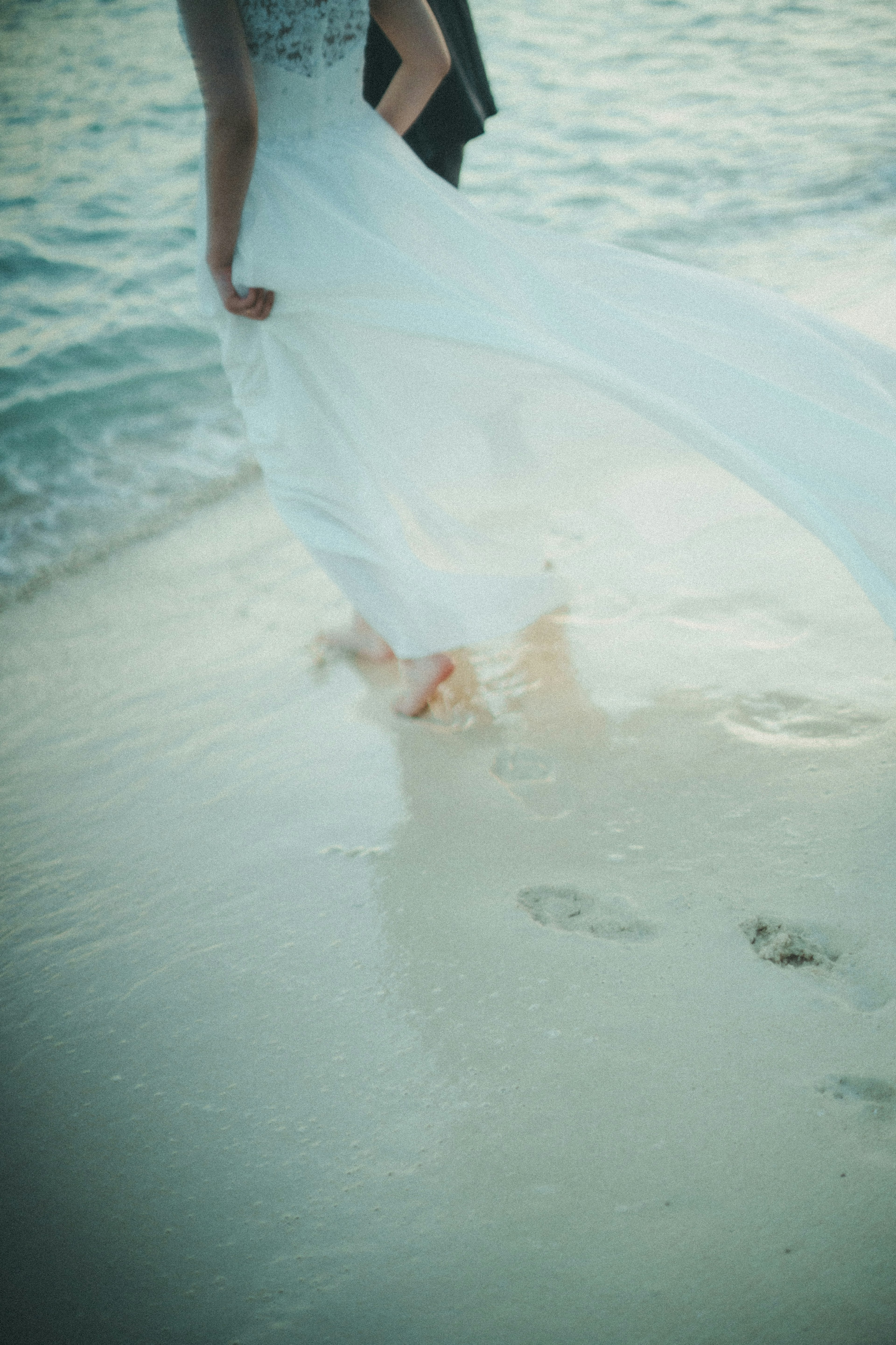 A woman in a white dress walking along the beach