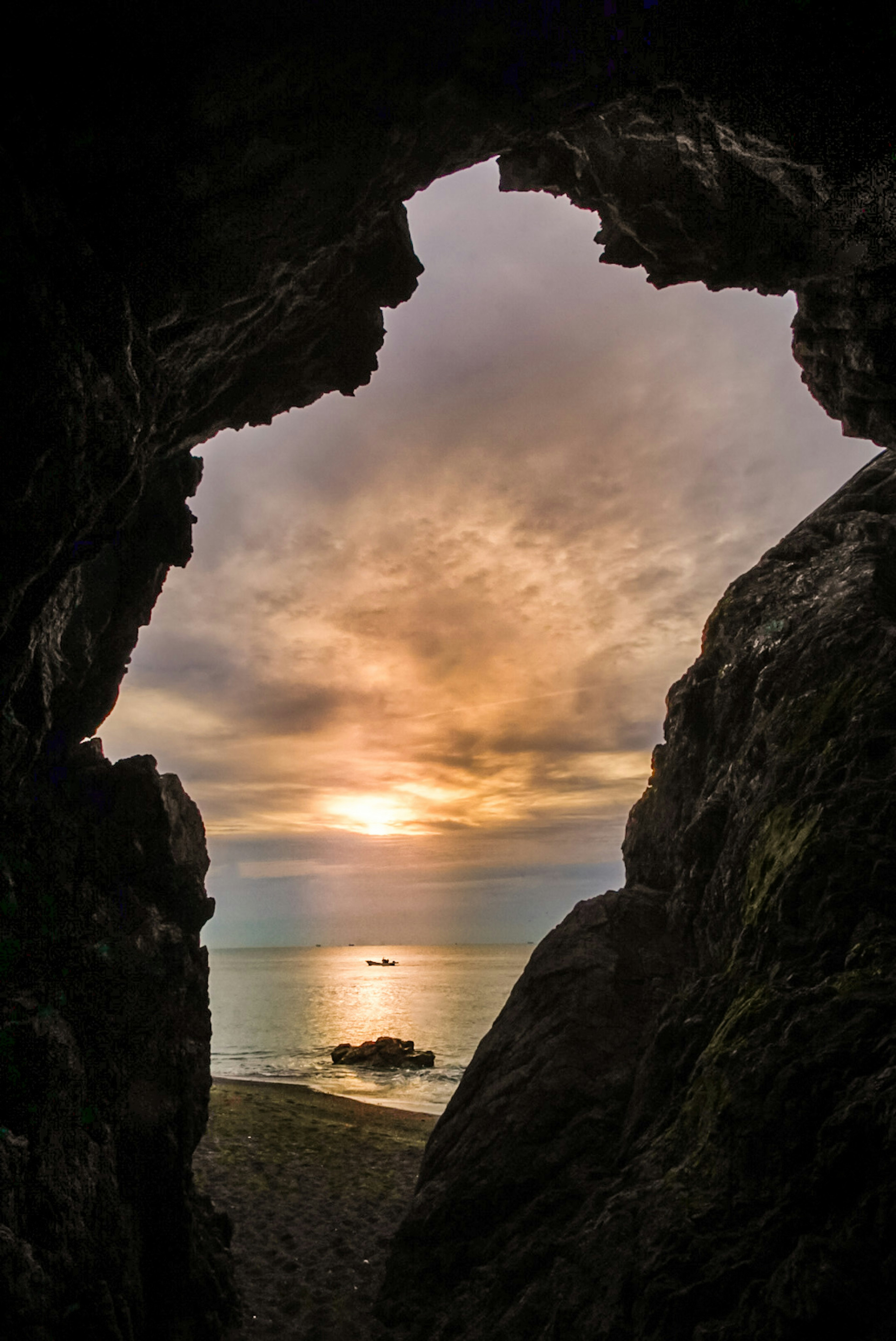 Blick auf das Meer und den Sonnenuntergang durch eine Felsöffnung