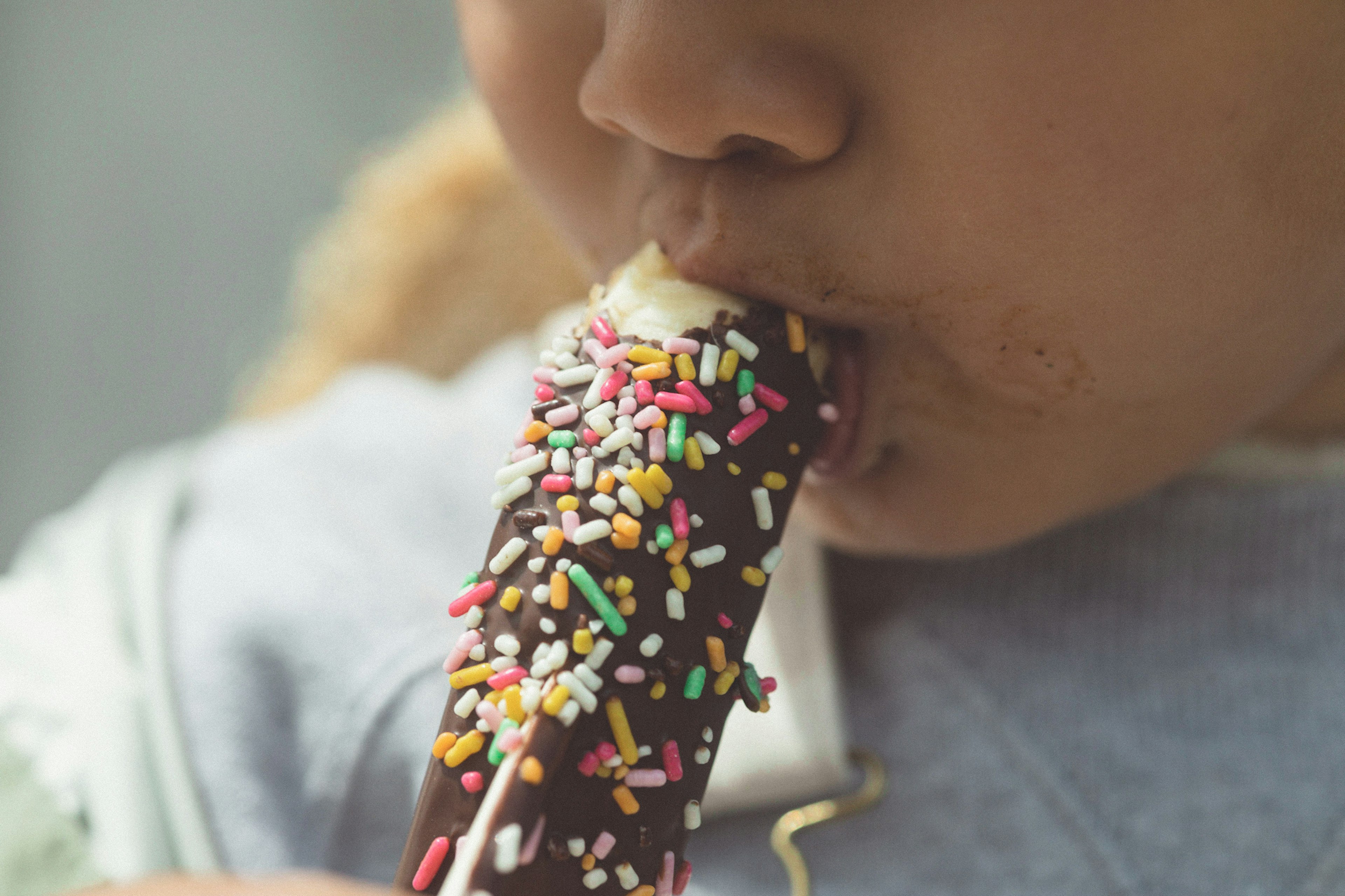 Close-up of a child eating a chocolate sprinkles ice cream