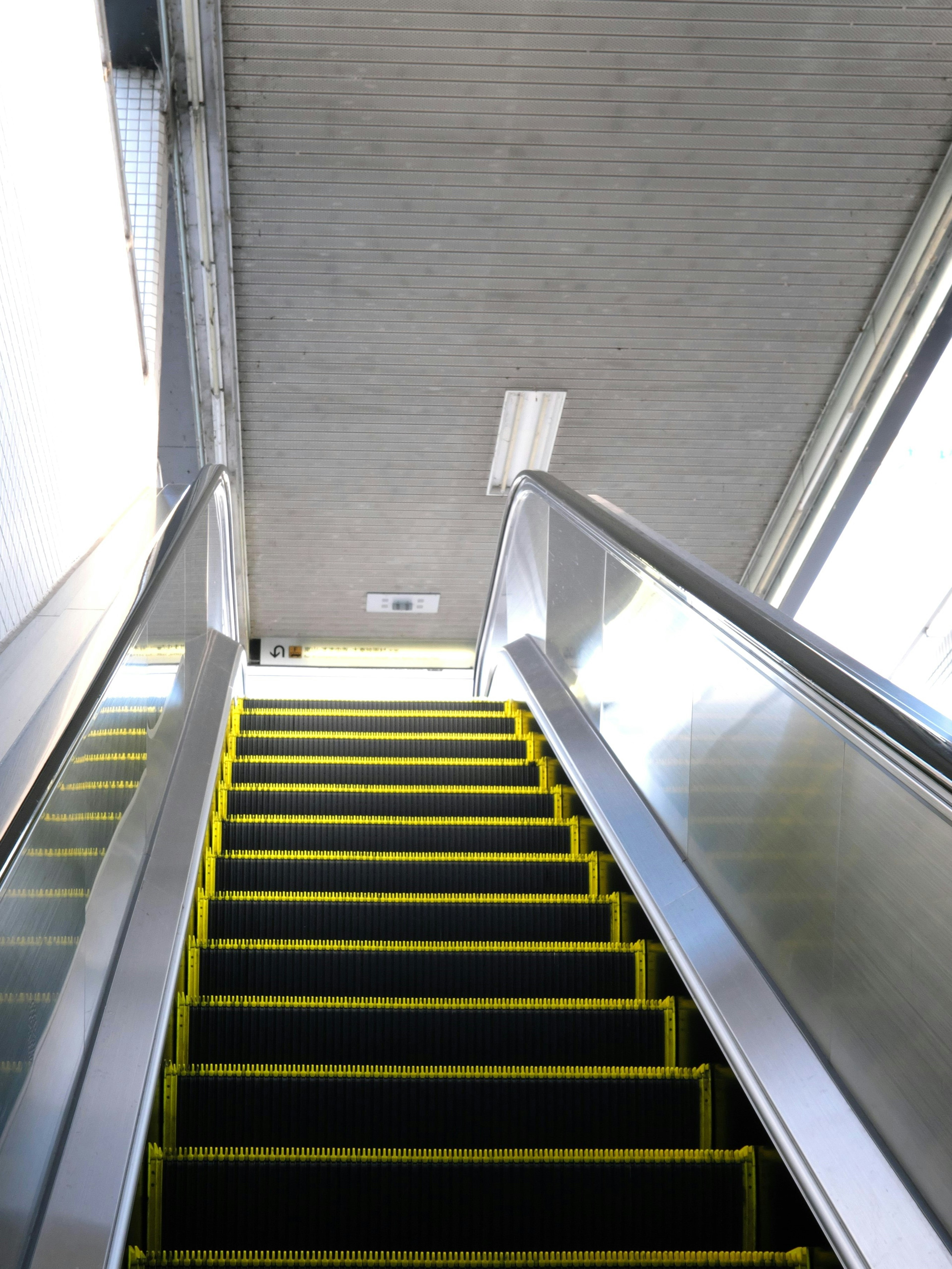 Image from the perspective of ascending stairs featuring bright lighting and metallic handrails