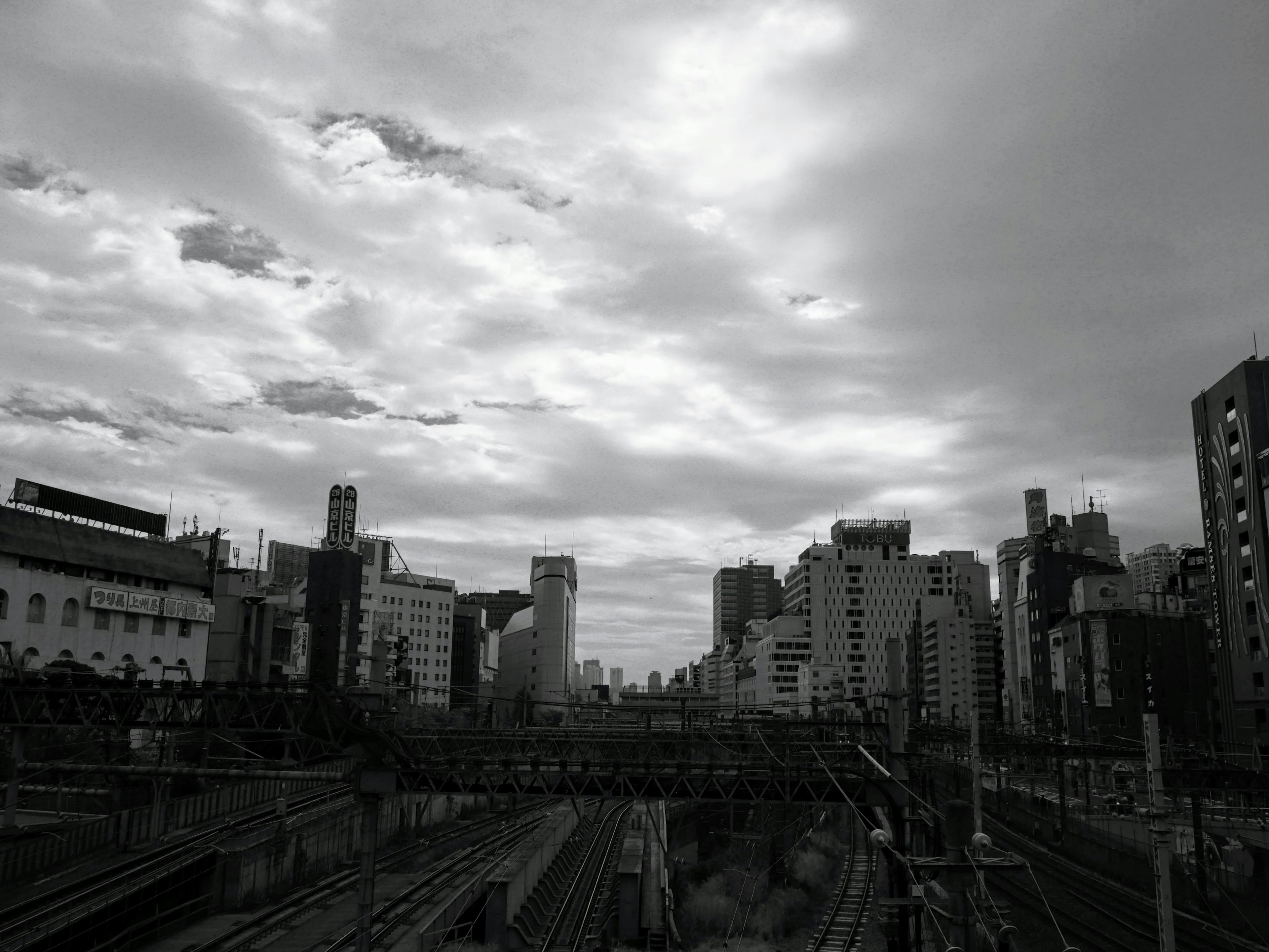 Monochrome photo capturing Tokyo's urban skyline and railway scenery