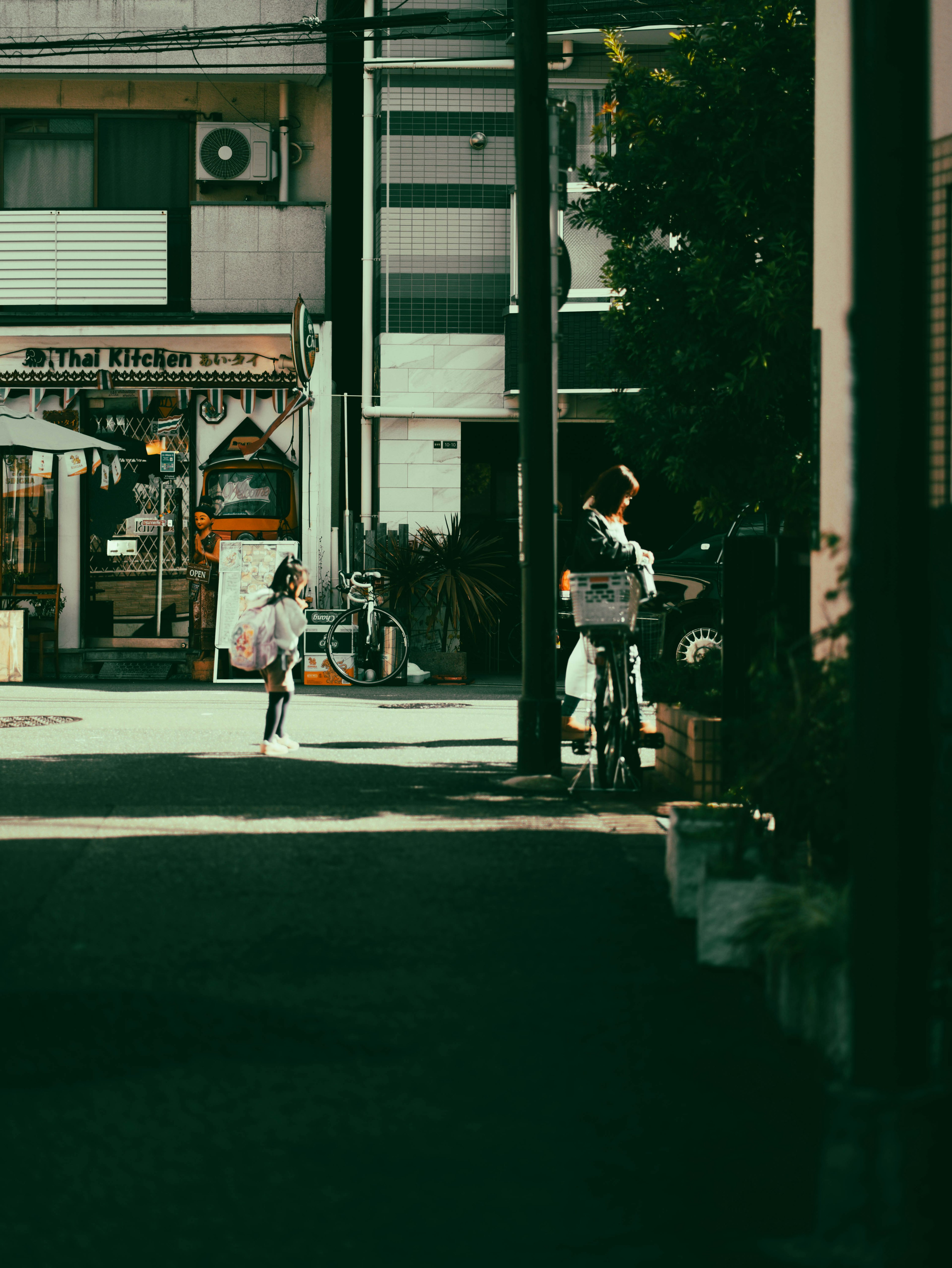 静かな通りに自転車に乗る子供と店舗の風景