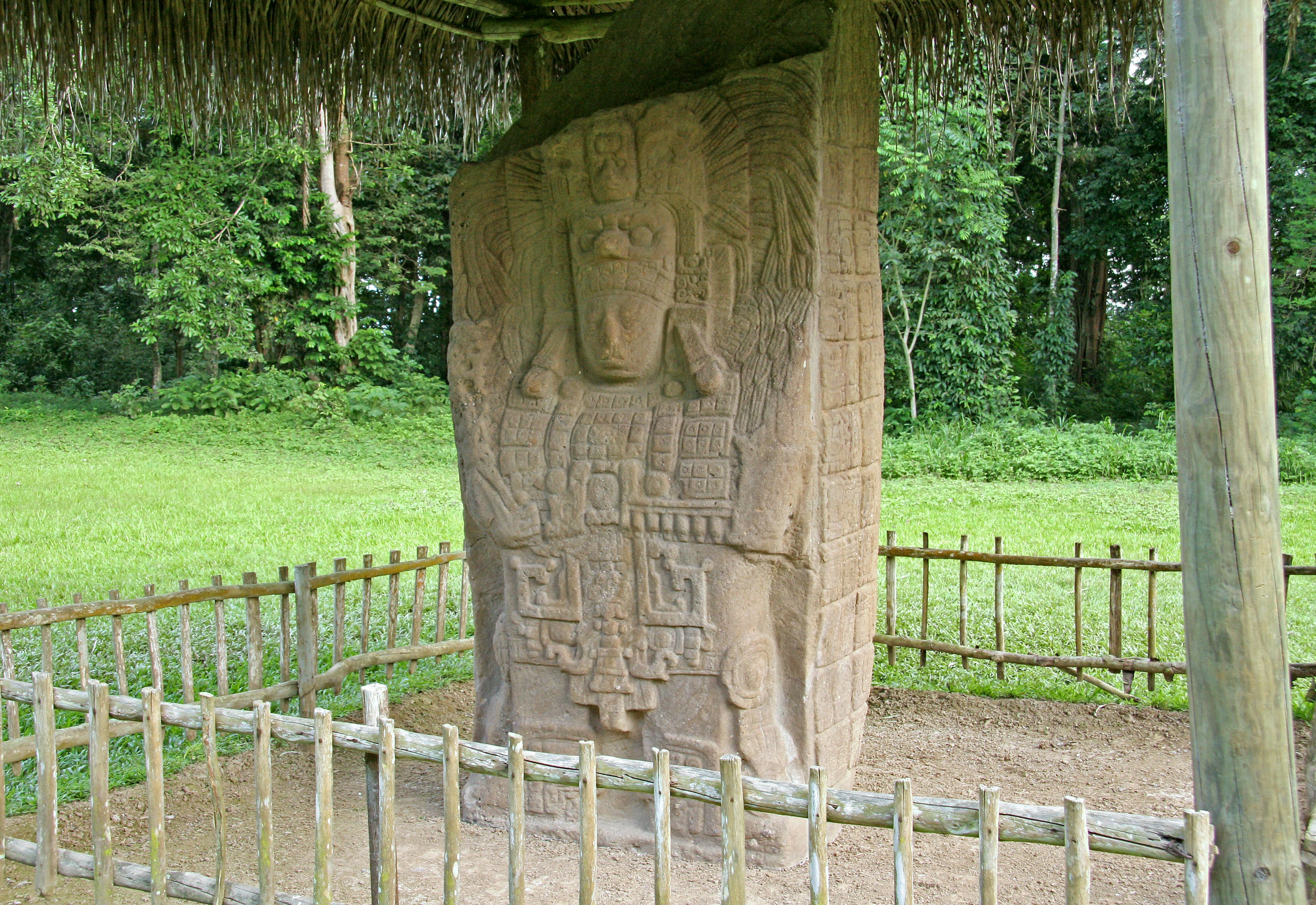 Una grande scultura in pietra all'interno di un'area recintata circondata da una vegetazione lussureggiante