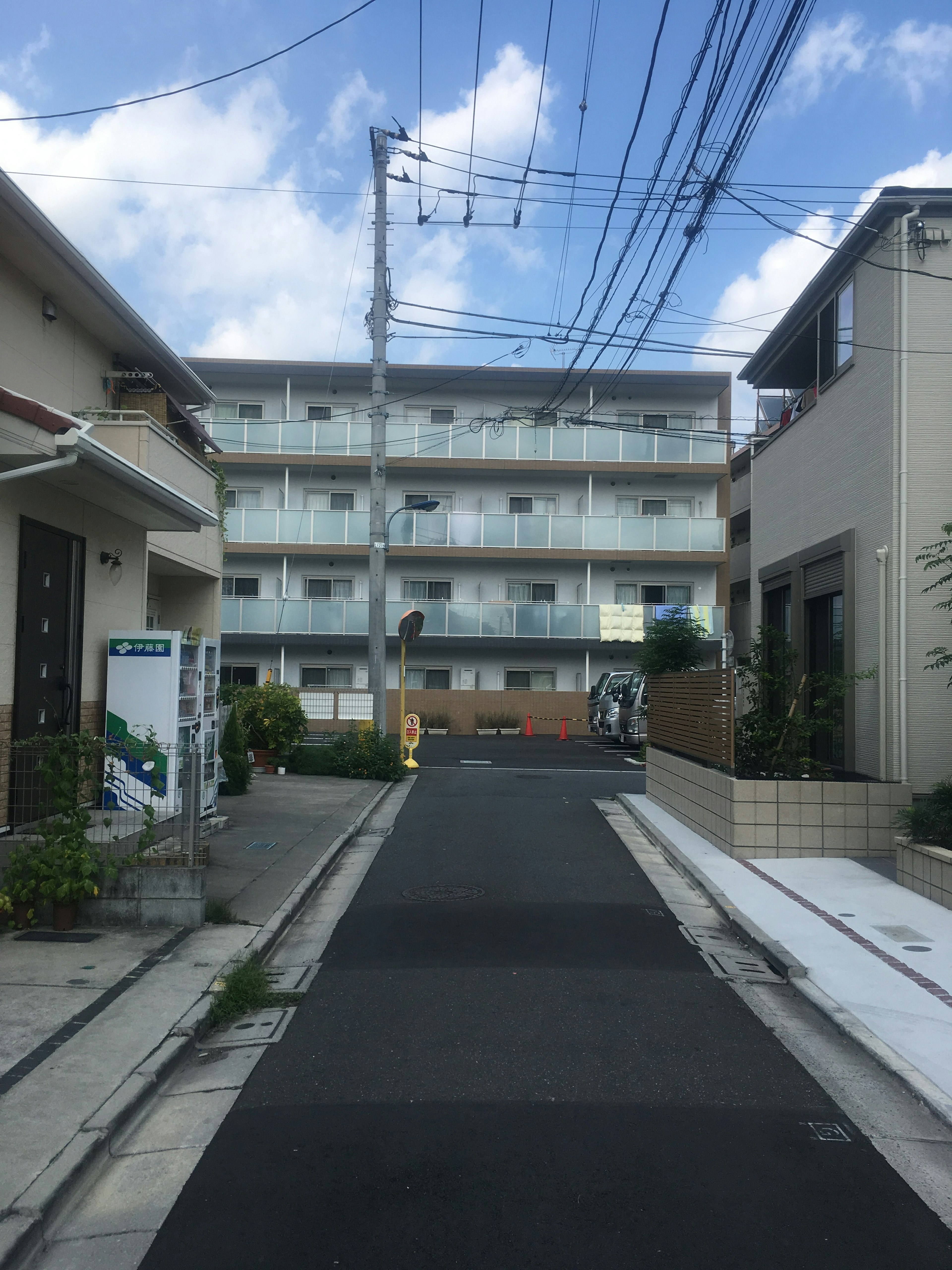 Street view of a residential area with an apartment building under blue sky