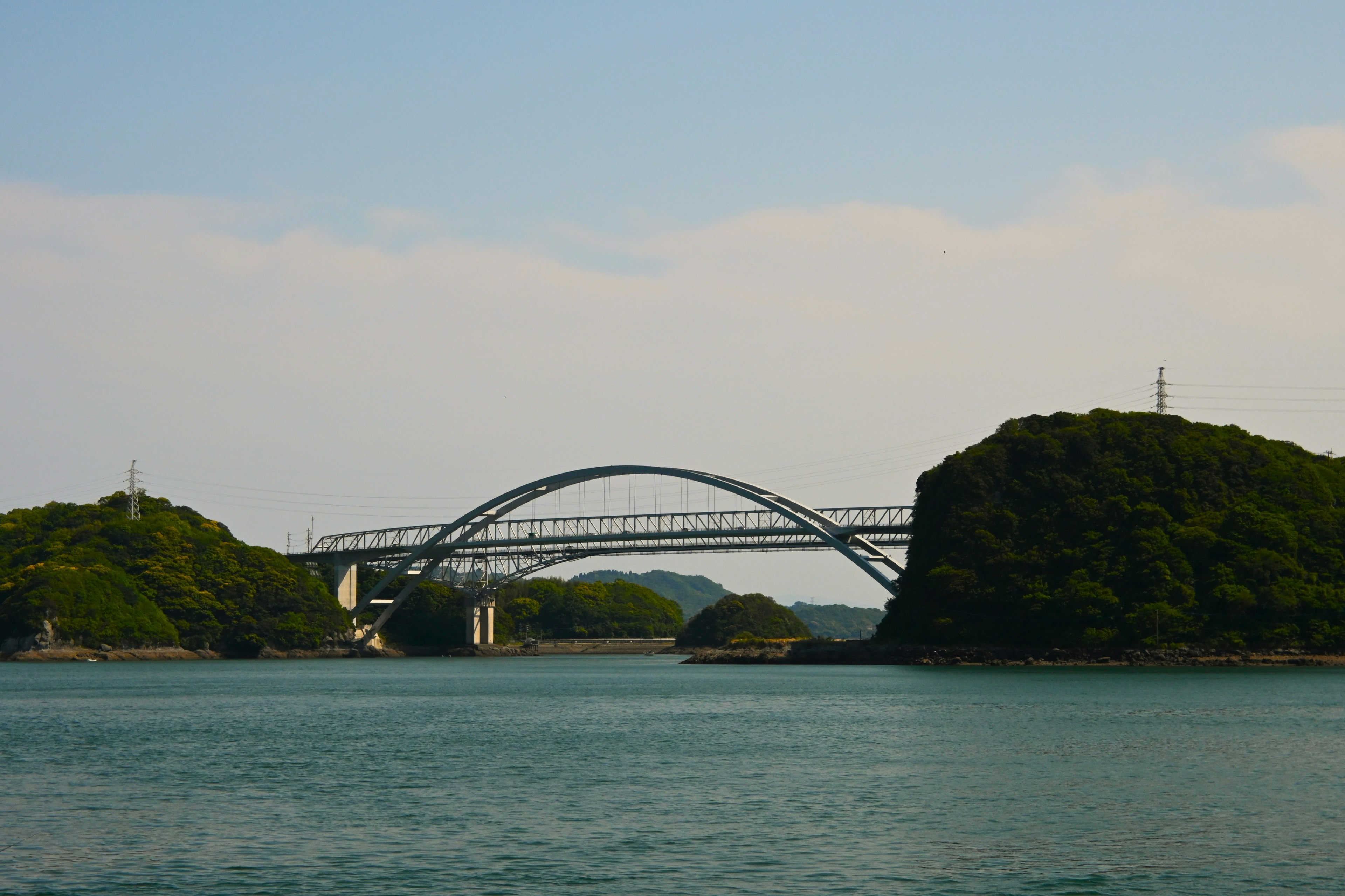 Jembatan lengkung yang indah membentang di laut dengan pulau-pulau hijau