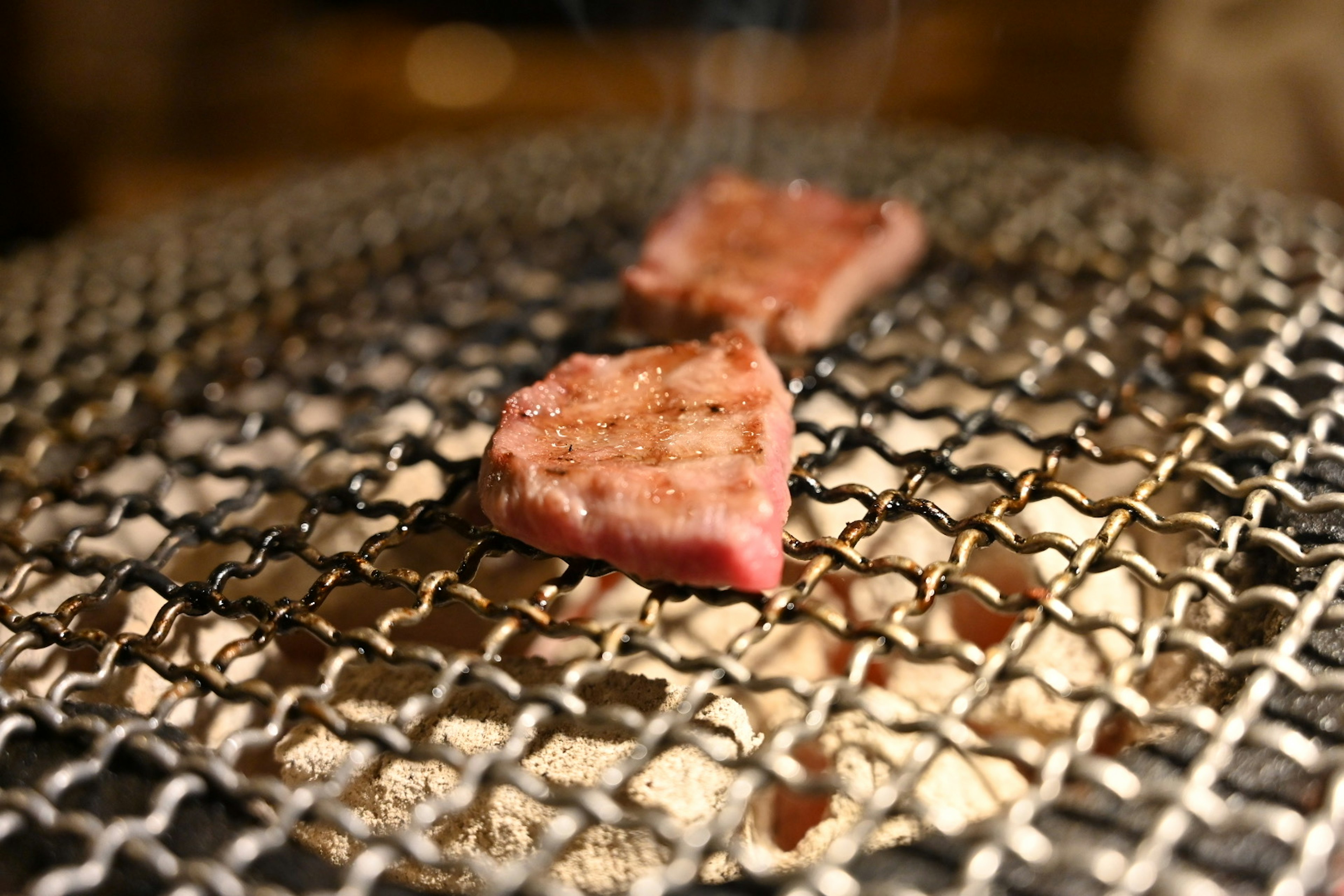 Fette di carne che si grigliano su una griglia a rete