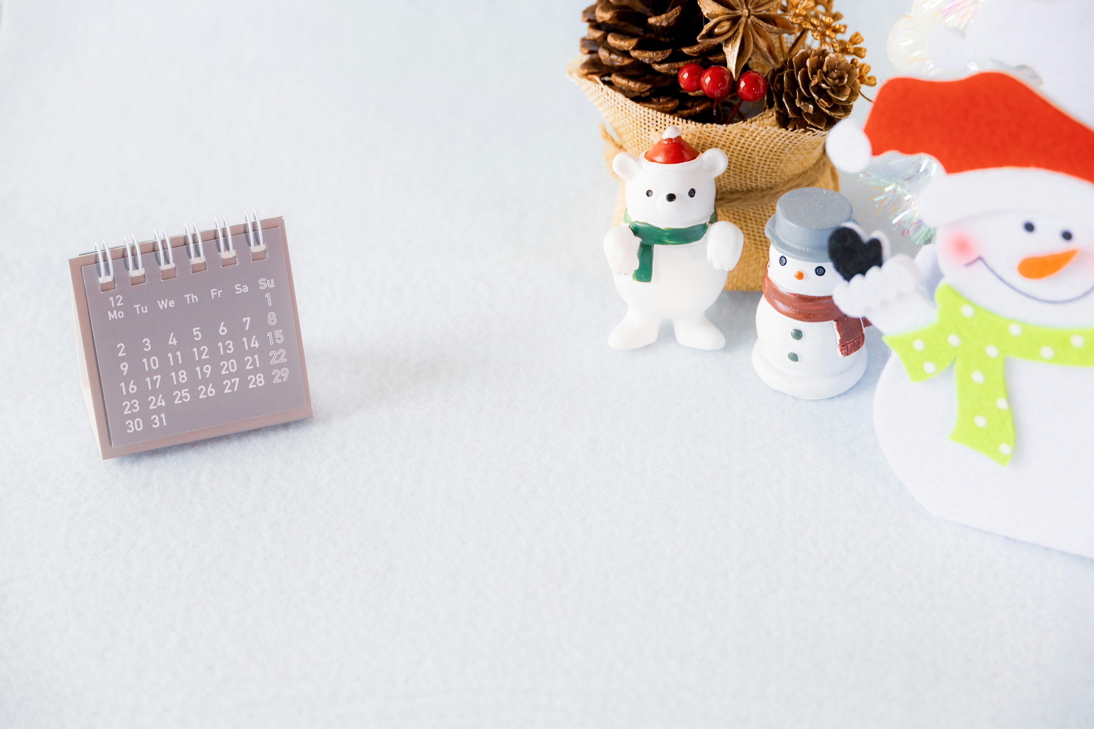 Small calendar next to cute snowman decorations and a pine cone