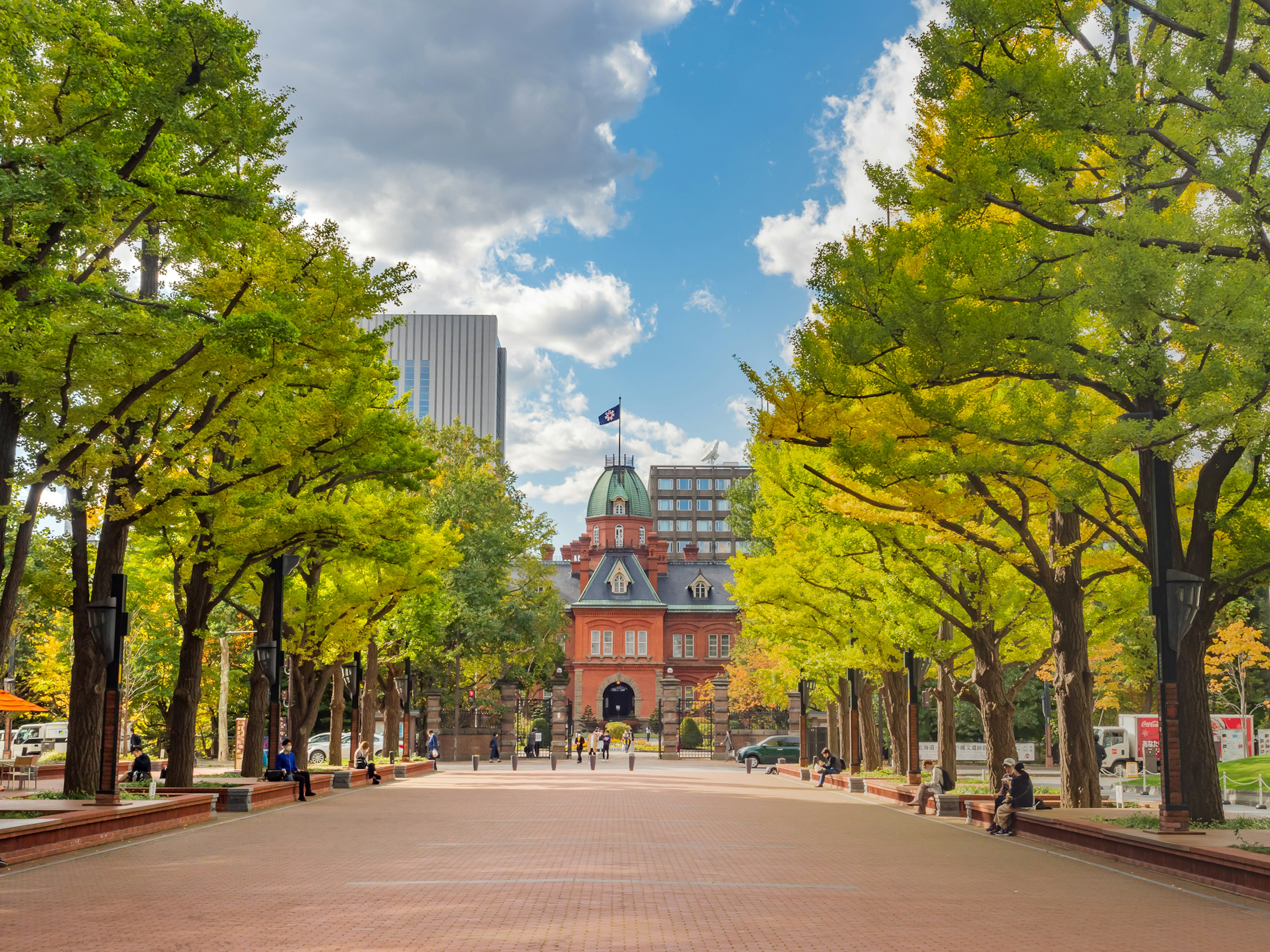 View of the red brick building with surrounding green trees and a clear sky