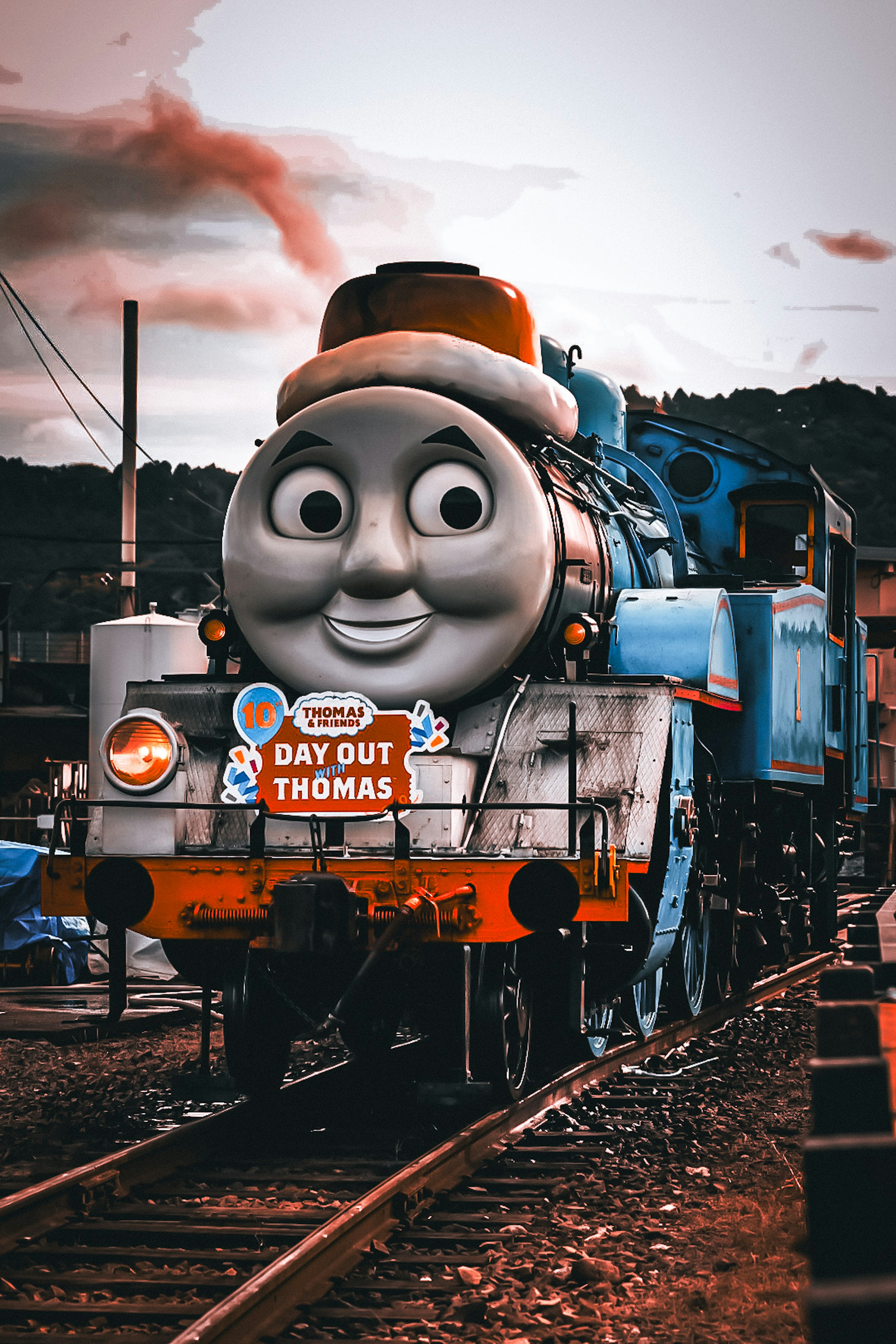 Sebuah lokomotif uap biru dengan wajah Thomas the Tank Engine diparkir di rel