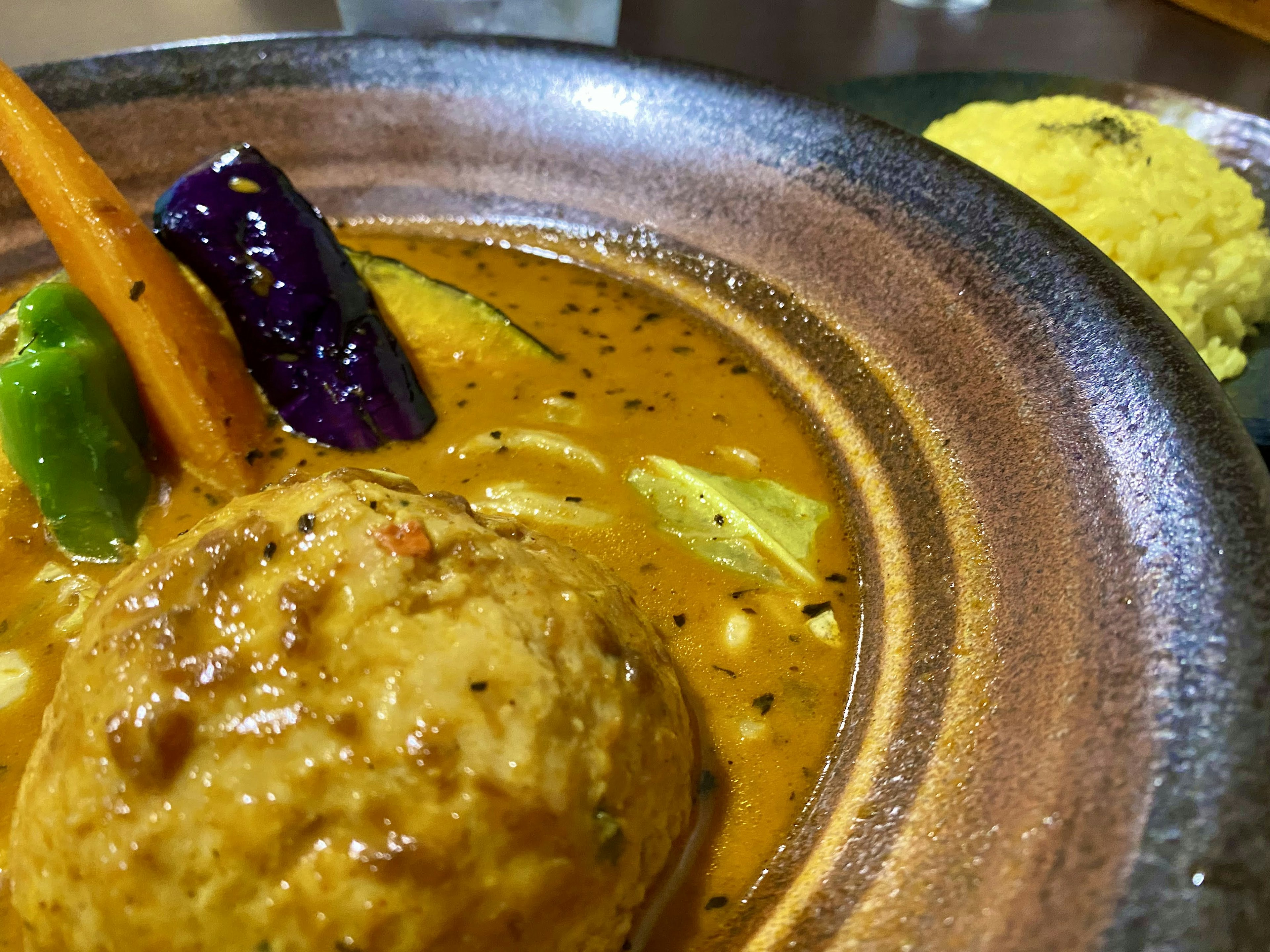 Bol de sauce au curry avec un gros dumpling et des légumes colorés