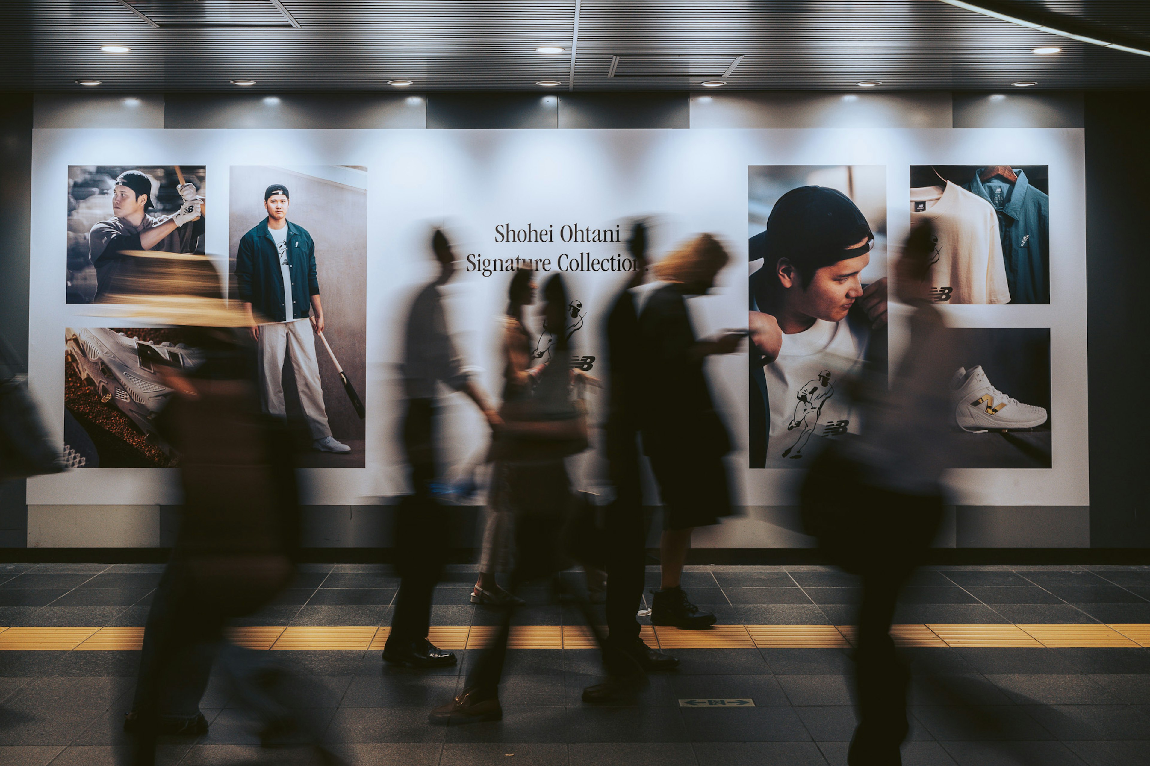 人々が通り過ぎる中にファッション広告が展示された駅の風景