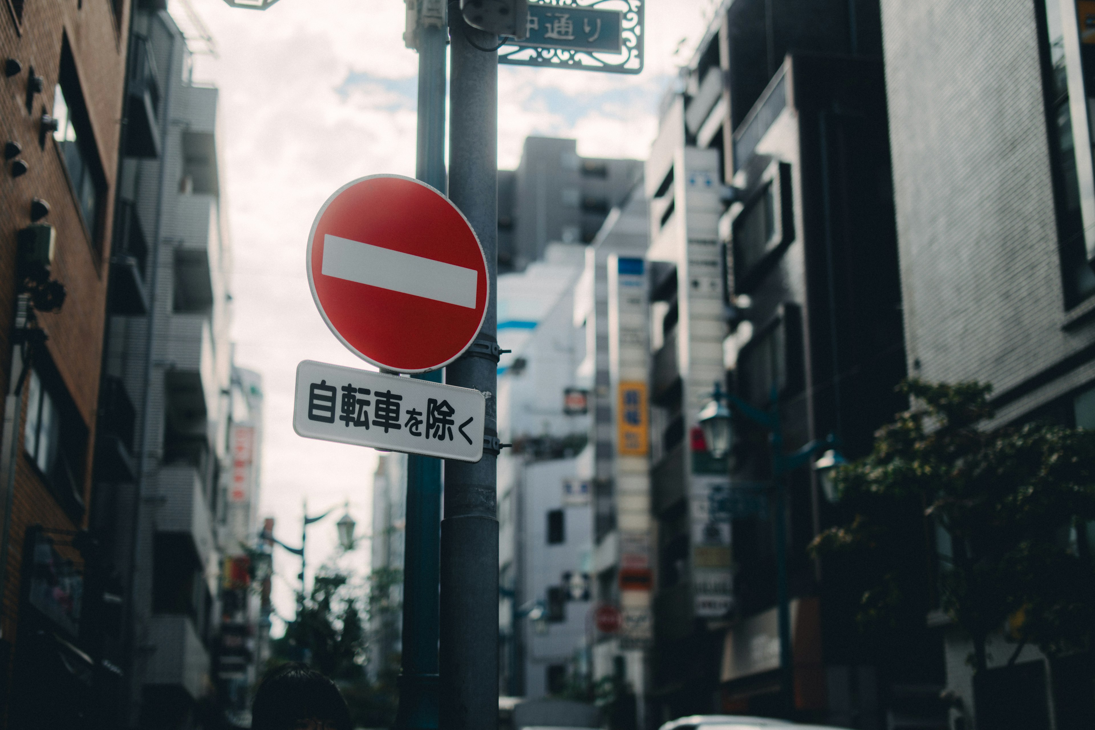 赤い禁止標識と日本語の自転車通行止めのサインがある街の風景