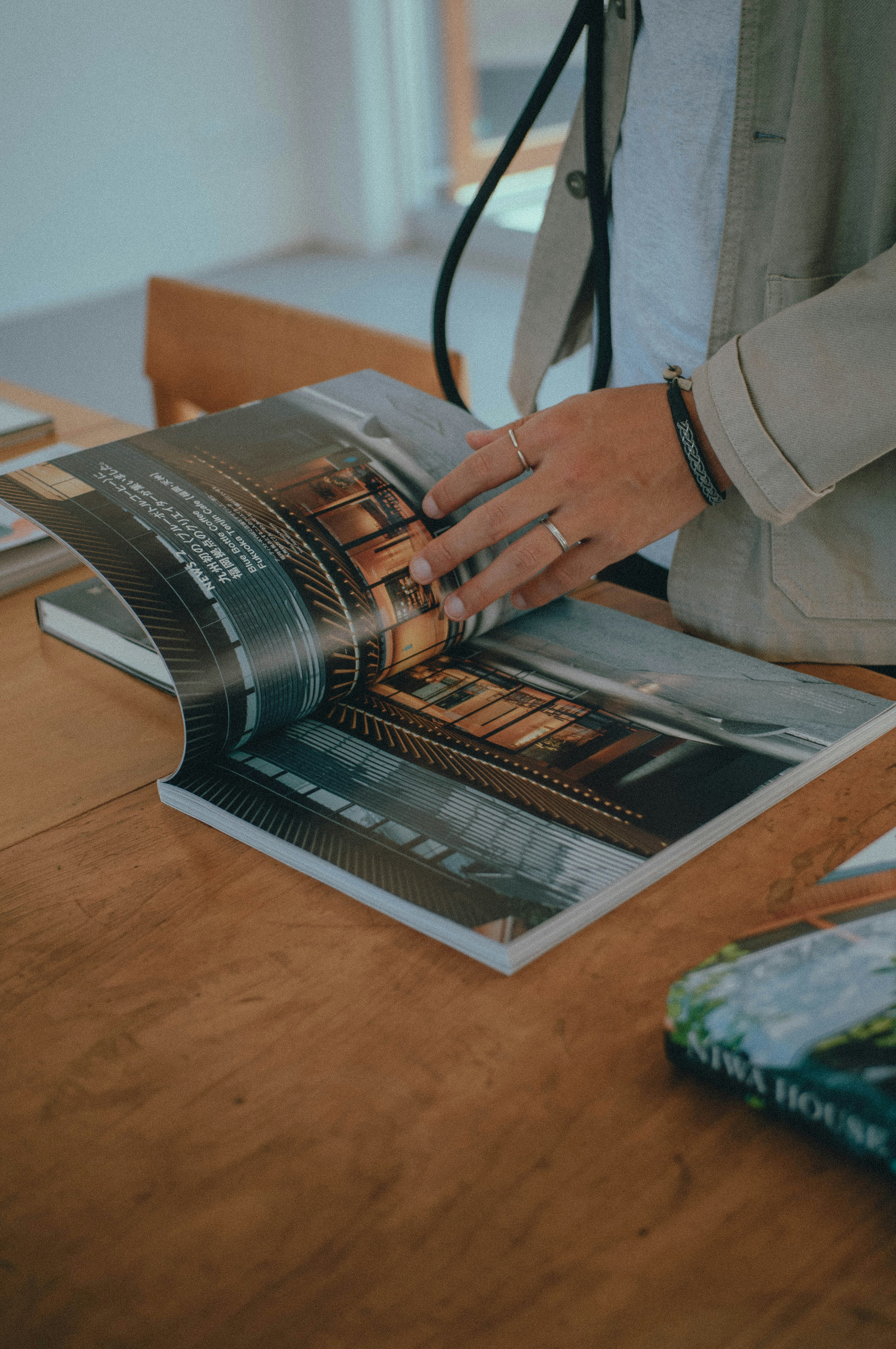 Gambar seseorang yang membolak-balik buku di atas meja kayu