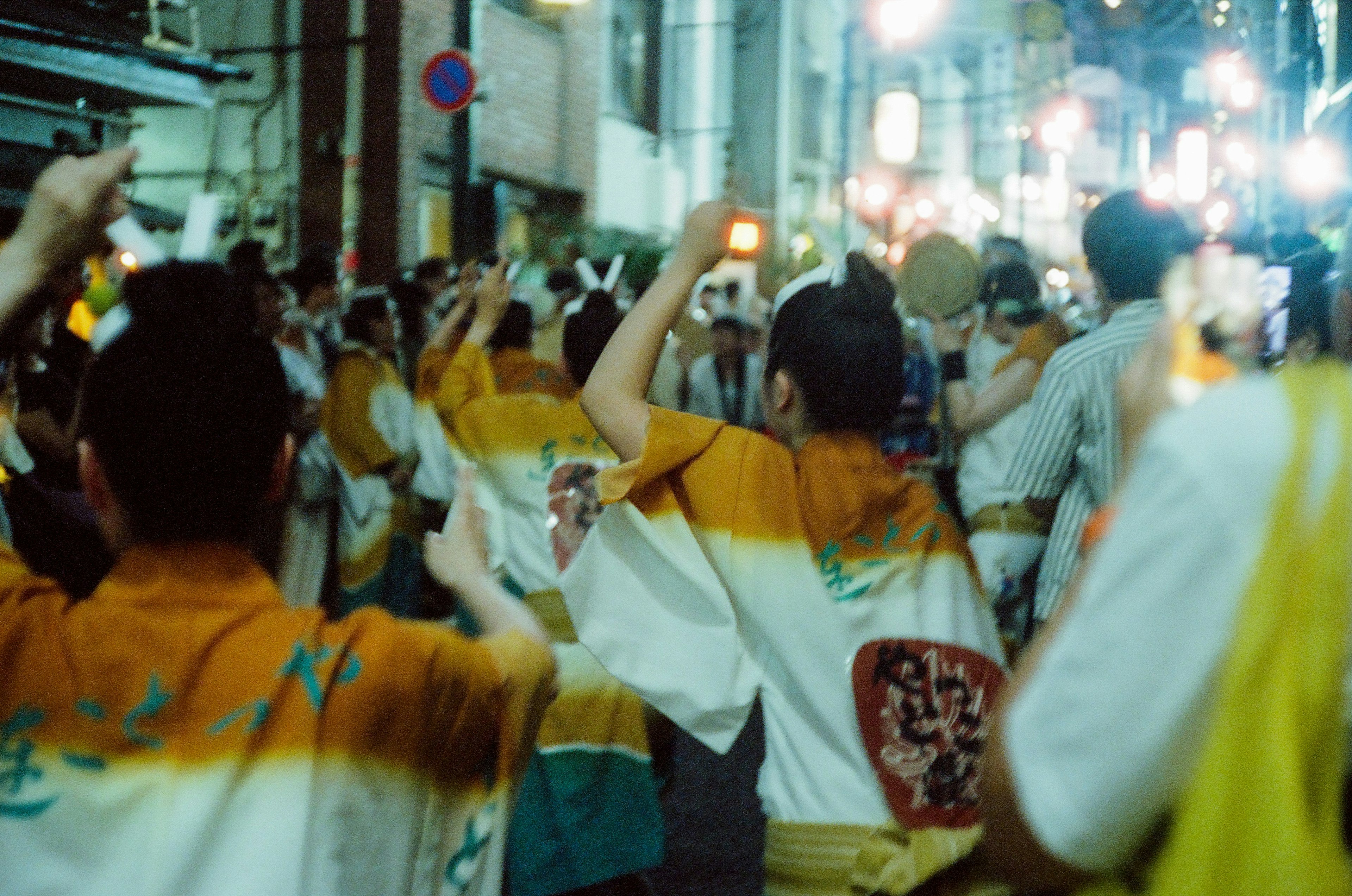 Multitud de personas bailando con trajes tradicionales durante un festival en una animada calle nocturna