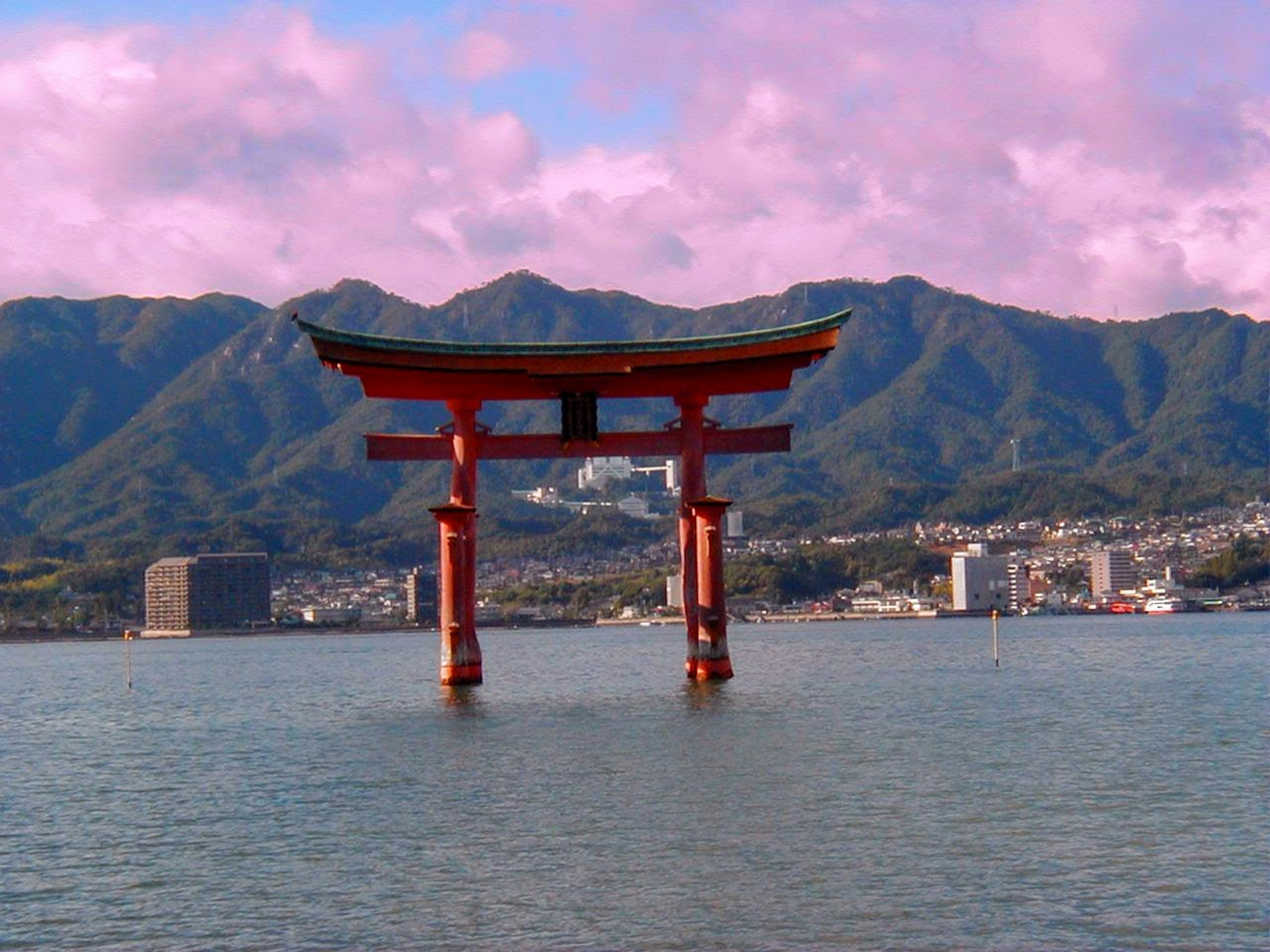 A beautiful red torii gate floating on water with mountains in the background