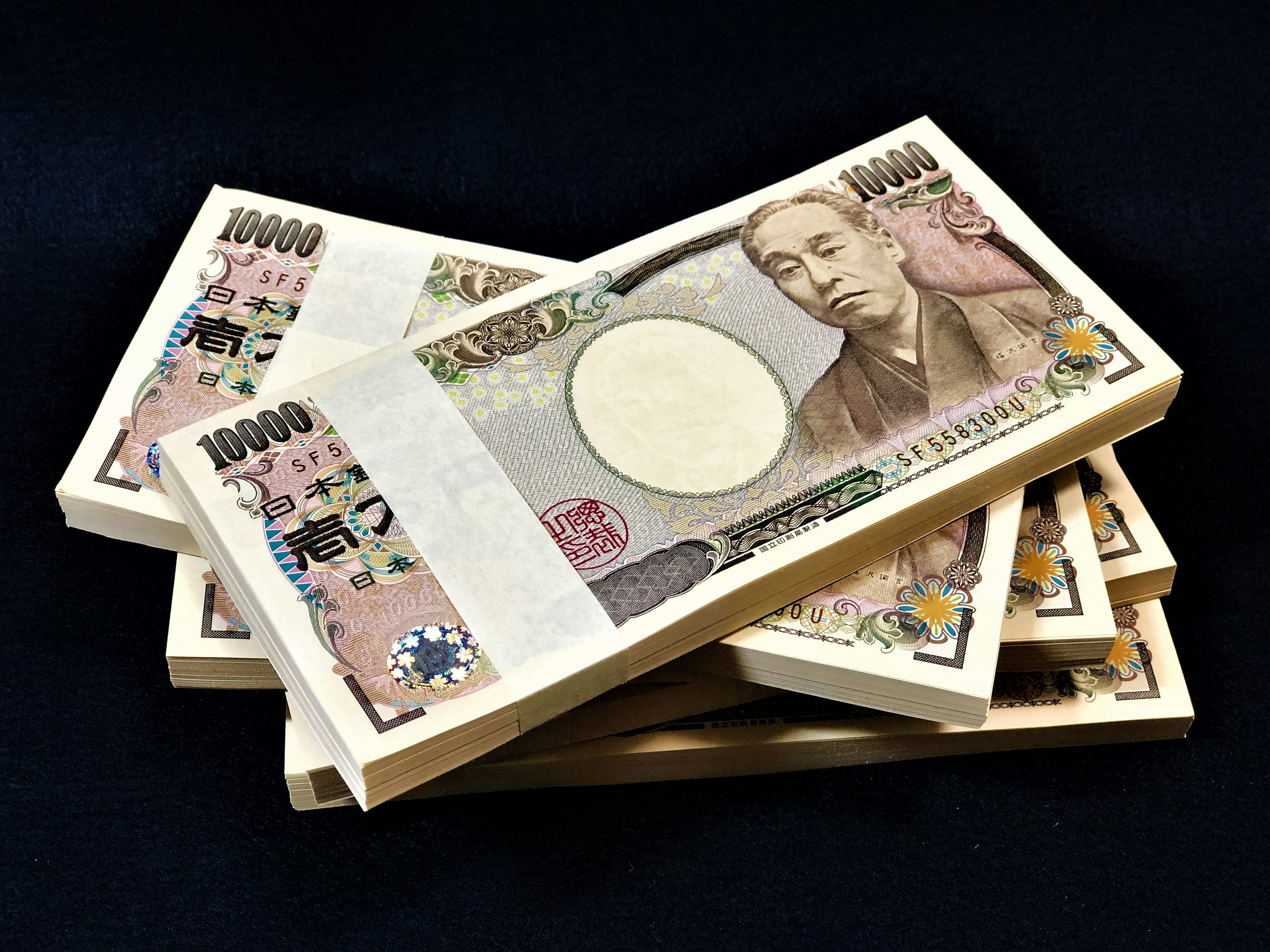 Stack of Japanese 10,000 yen bills on a dark background