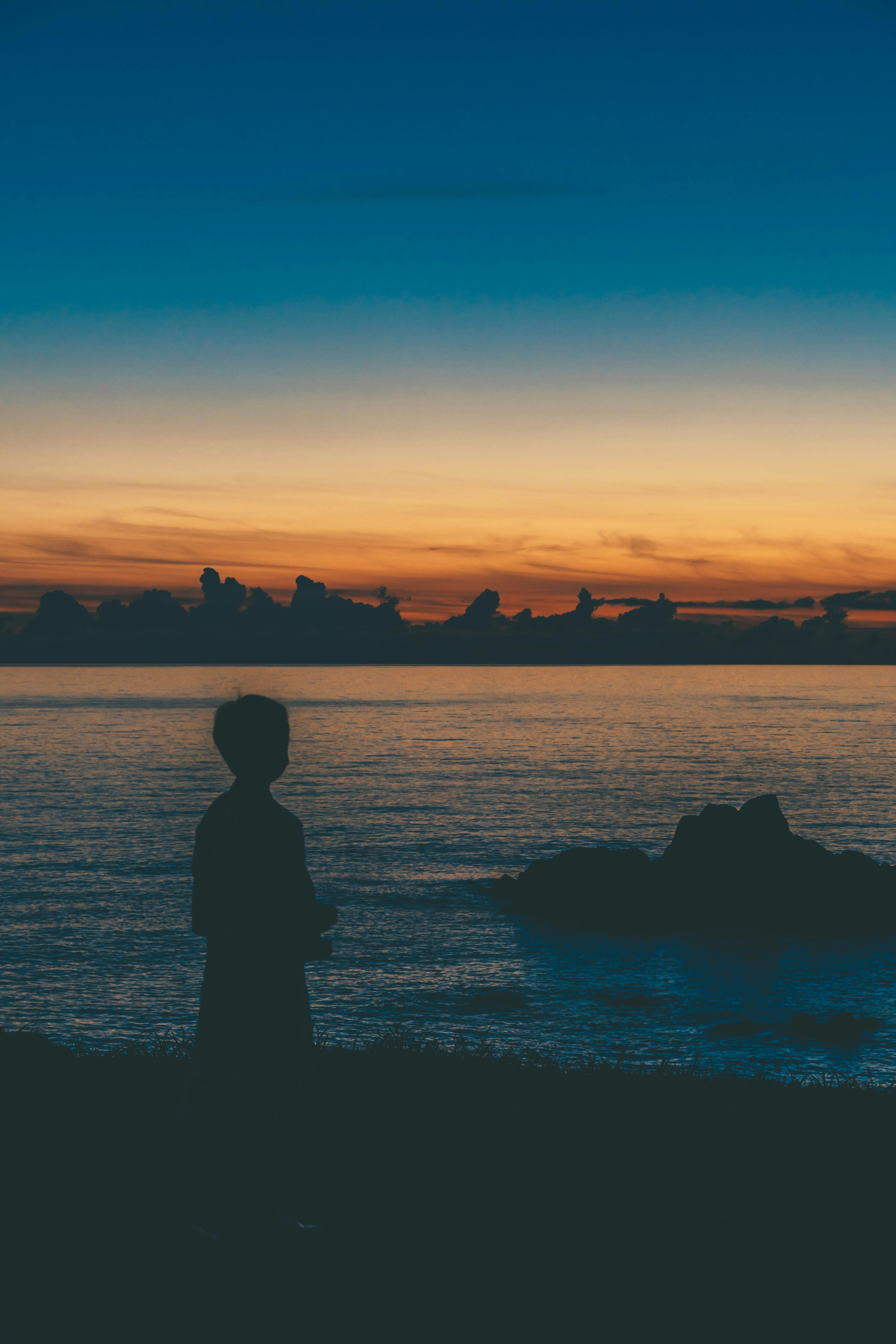 Silhouette einer Person, die am Meer bei Sonnenuntergang steht