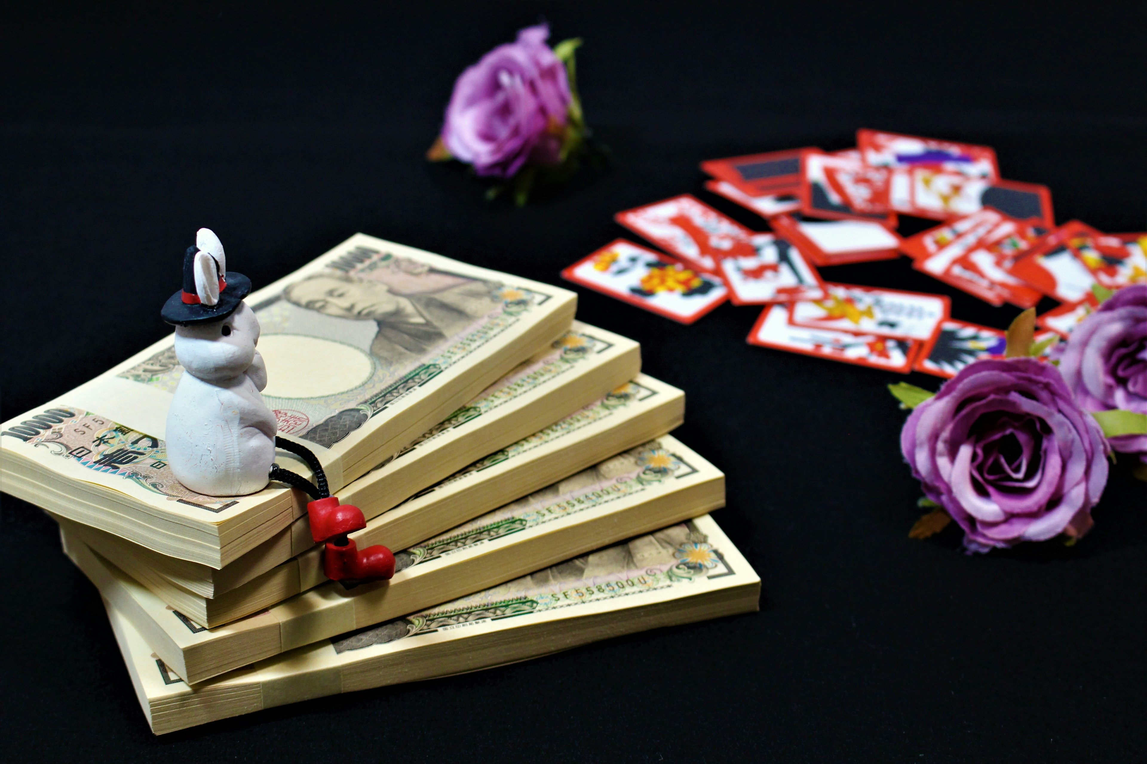 Un bonhomme de neige blanc assis sur des billets empilés avec des roses violettes et des cartes de jeu sur un fond noir